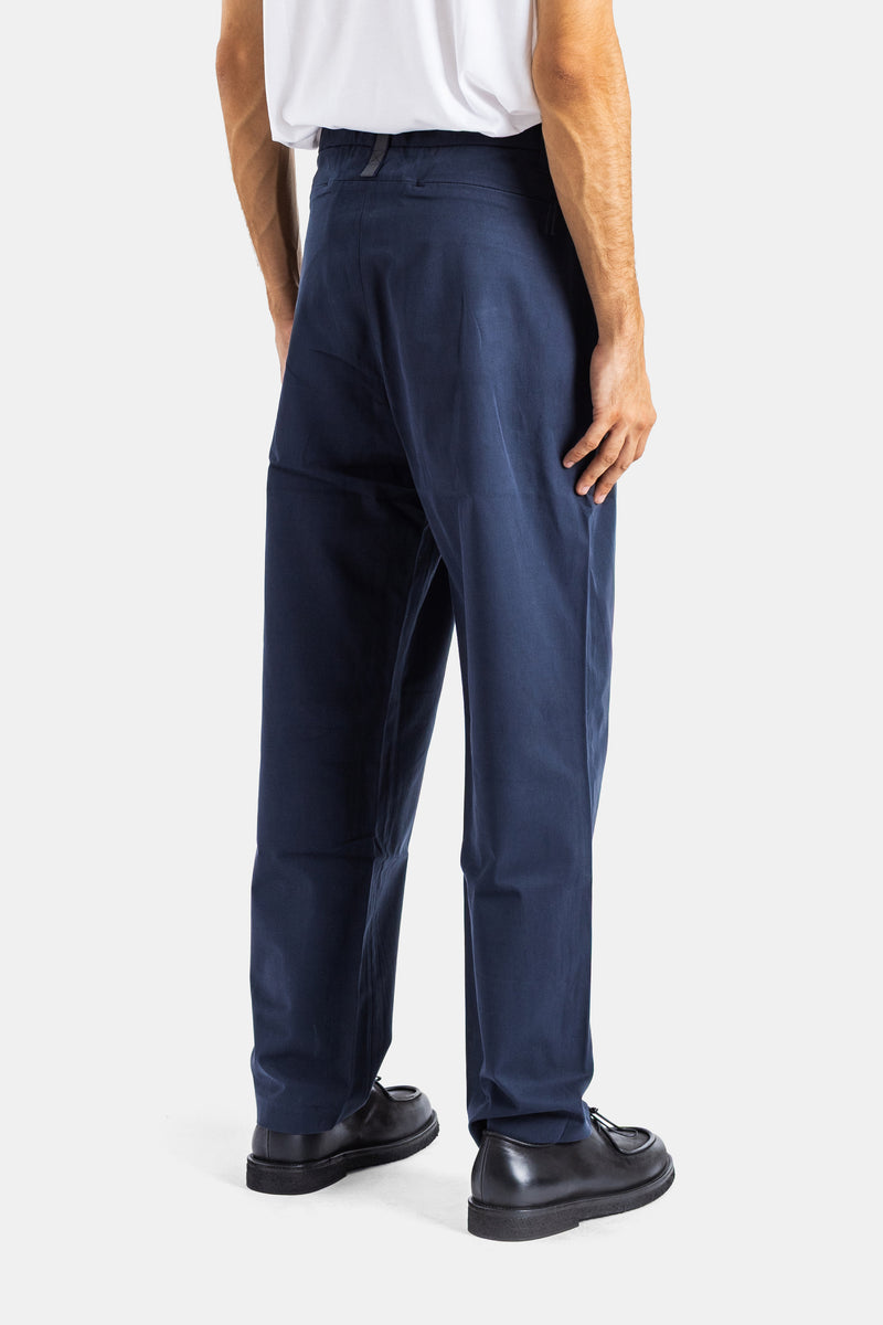 Rear view of Sease men's navy blue tech pants featuring an elastic waistband and black tassel loafers.