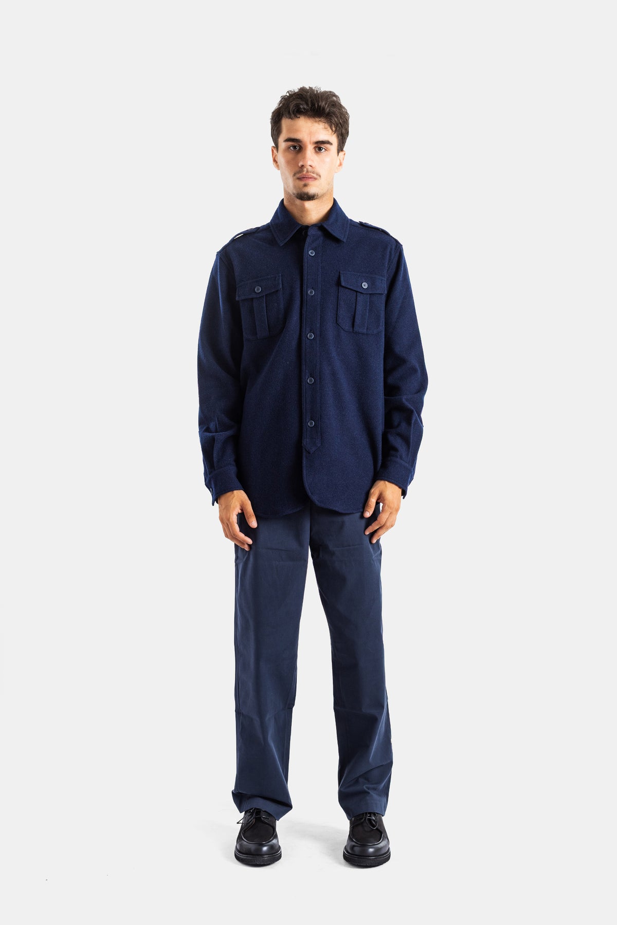 Sease men's navy blue tech chino pants styled with a matching wool overshirt and black derby shoes.