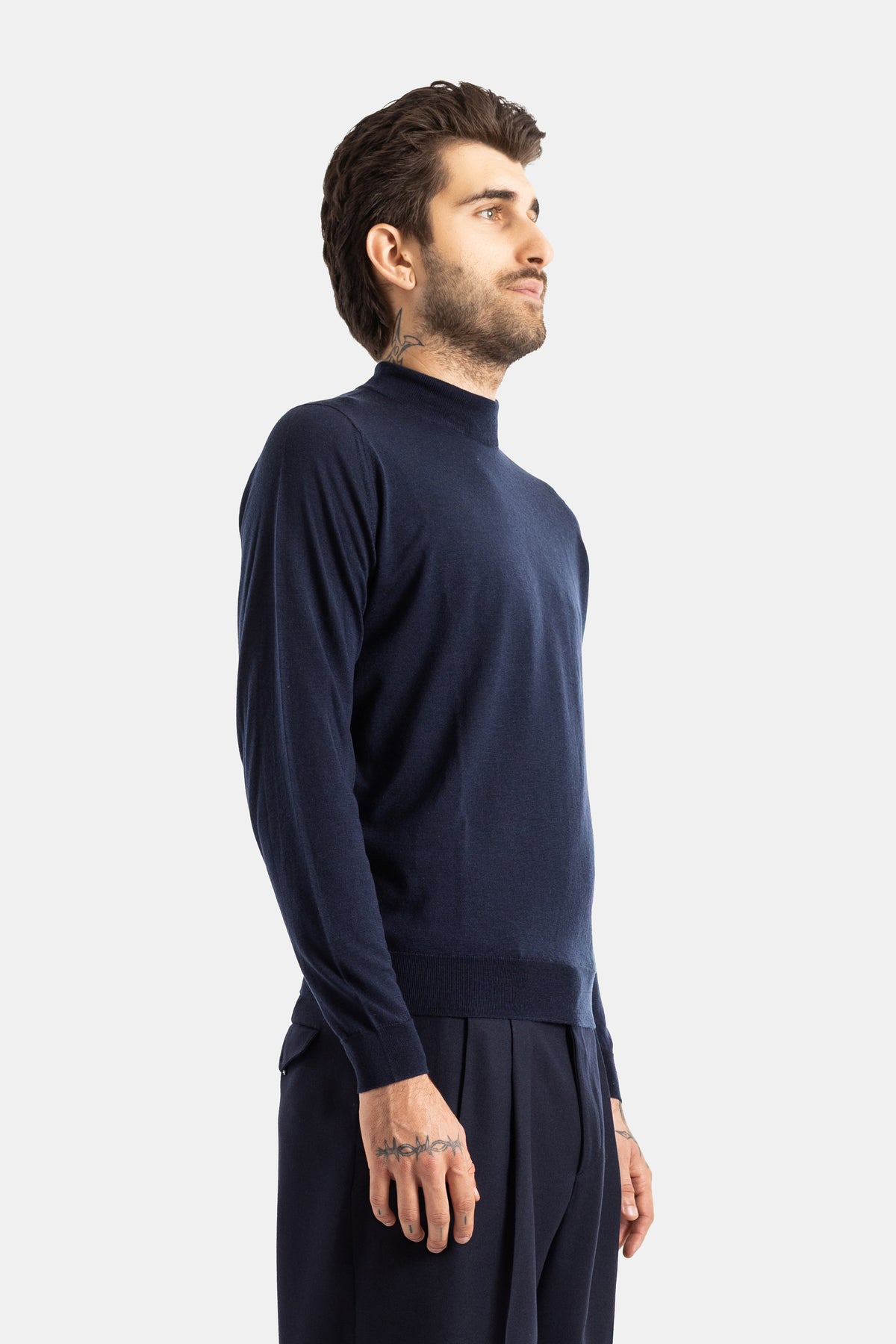 Smedley pull col montant mérinos bleu nuit vue de profil, coupe slim et tatouages visibles sur la main
