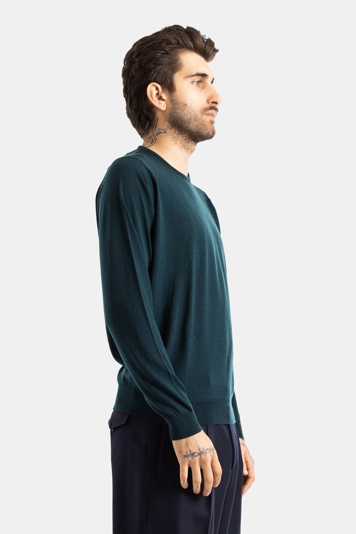 Smedley pull laine mérinos vert sapin vue de profil homme tatouages pantalon marine coupe épurée