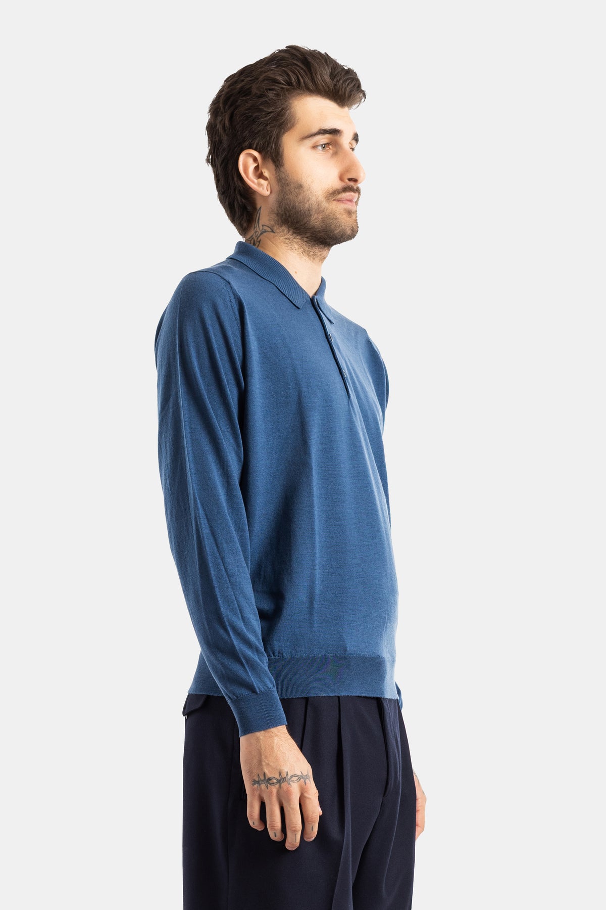 Smedley polo manches longues laine mérinos bleu vue de profil, texture tricot fin et bas côte, porté avec pantalon marine