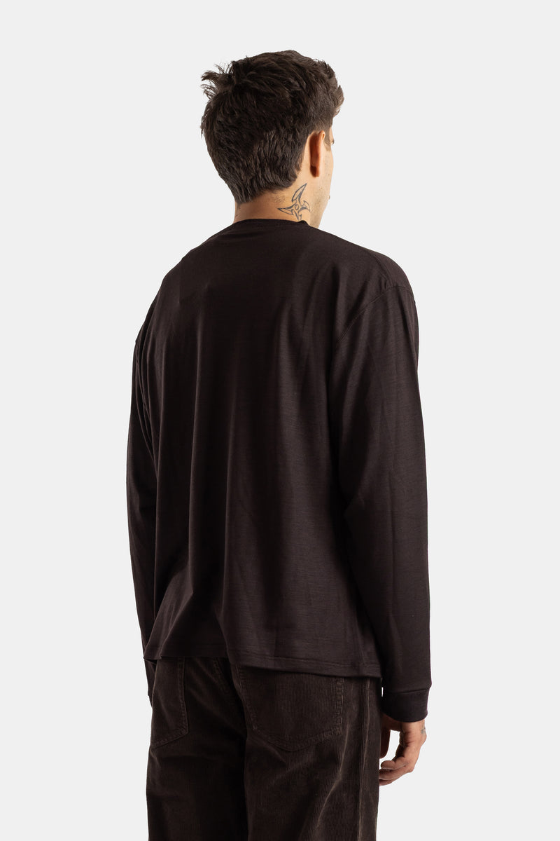 Back view of the men's dark brown Studio Nicholson Pinhas t-shirt with raglan sleeves and a neck tattoo.