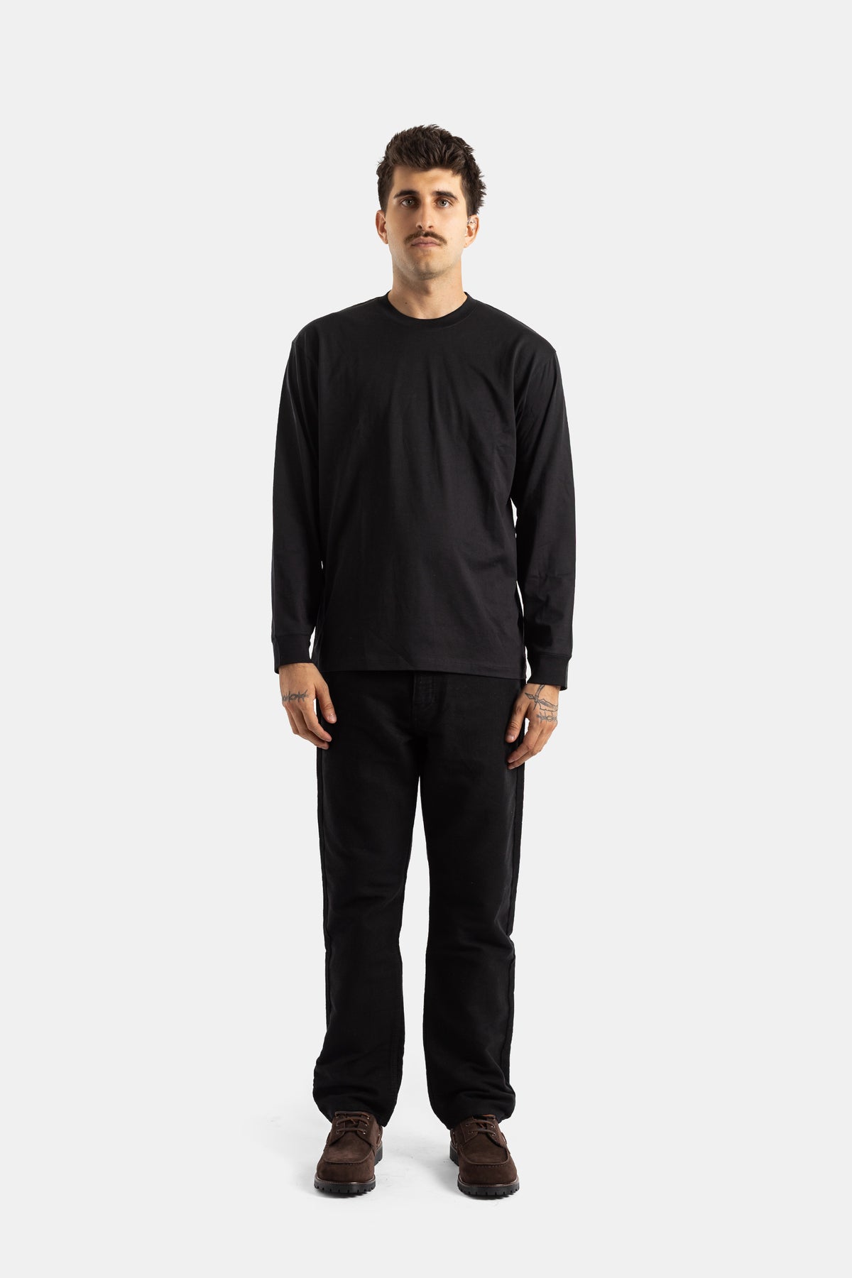 Studio Nicholson men's straight black jeans with a black long sleeve and dark brown boots, full look.
