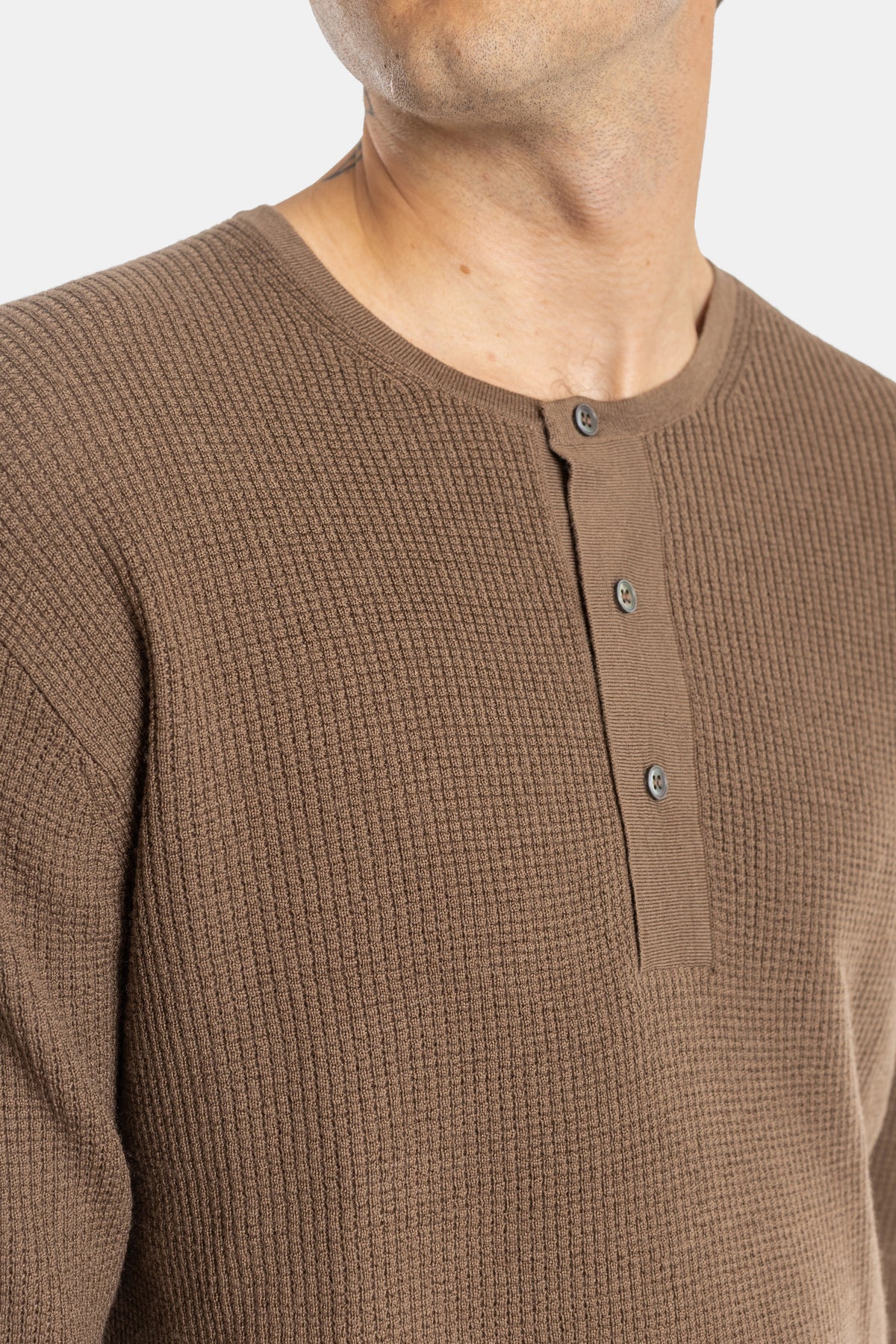 Close-up of Studio Nicholson brown waffle henley showing the three-button placket and textured relief.