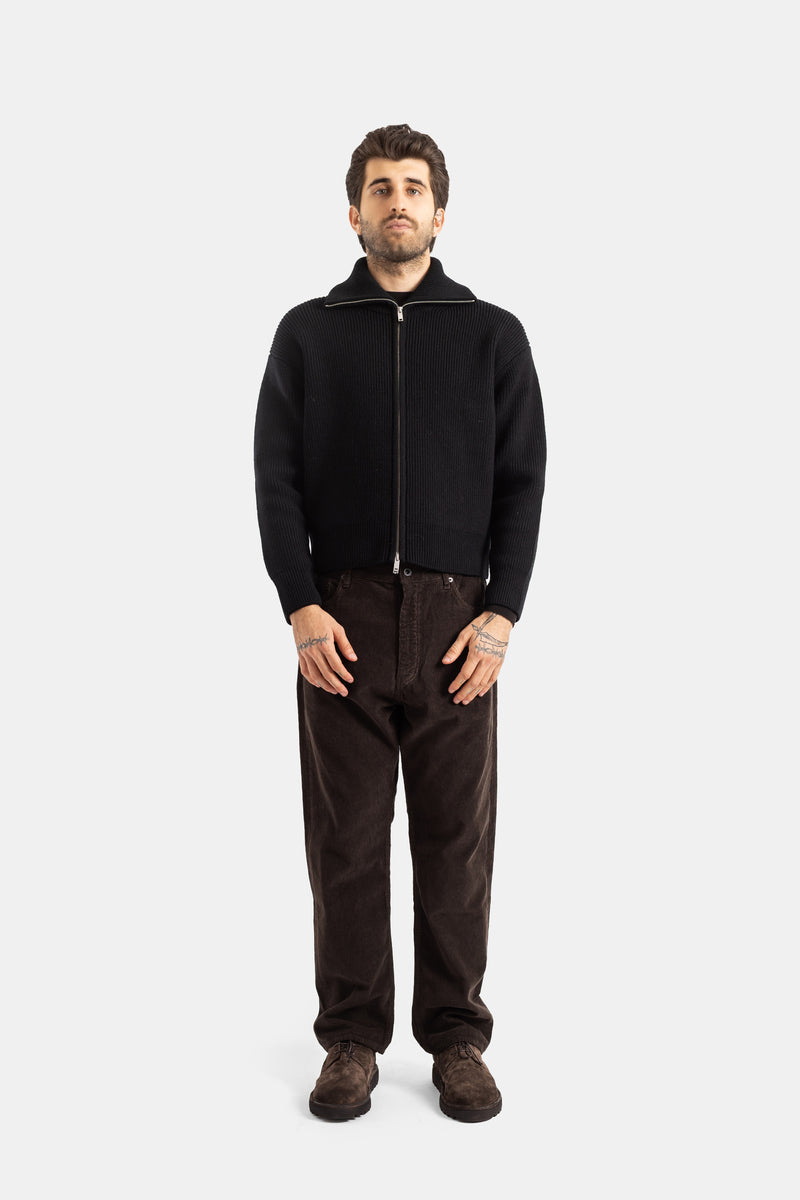 Studio Nicholson cardigan zippé noir côtelé porté face entière, look automne homme avec pantalon velours brun