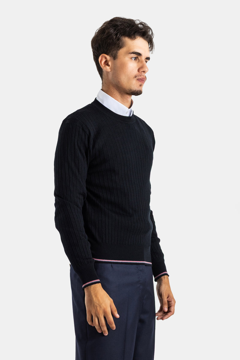 Schwarzer Thom Browne Herrenpullover getragen über weißem Hemd und blauer Hose, Dreiviertel-Profilansicht.