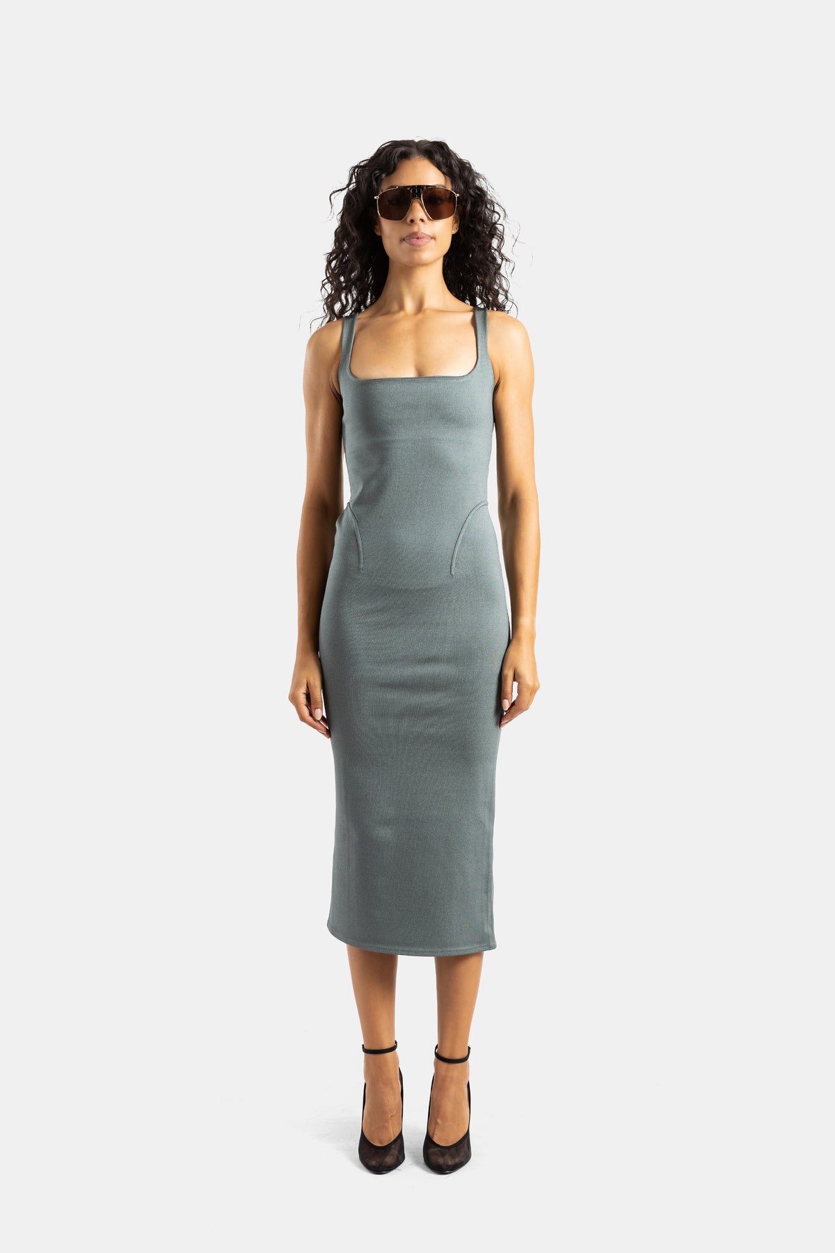 Maison Alaïa front view of textured grey-green knit sheath dress with fitted seams and aviator sunglasses