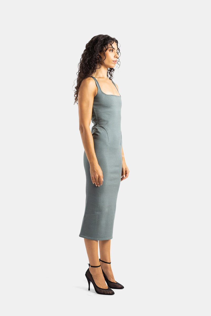 Maison Alaïa profile silhouette of a grey-green sheath midi knit dress worn with sophisticated black pumps