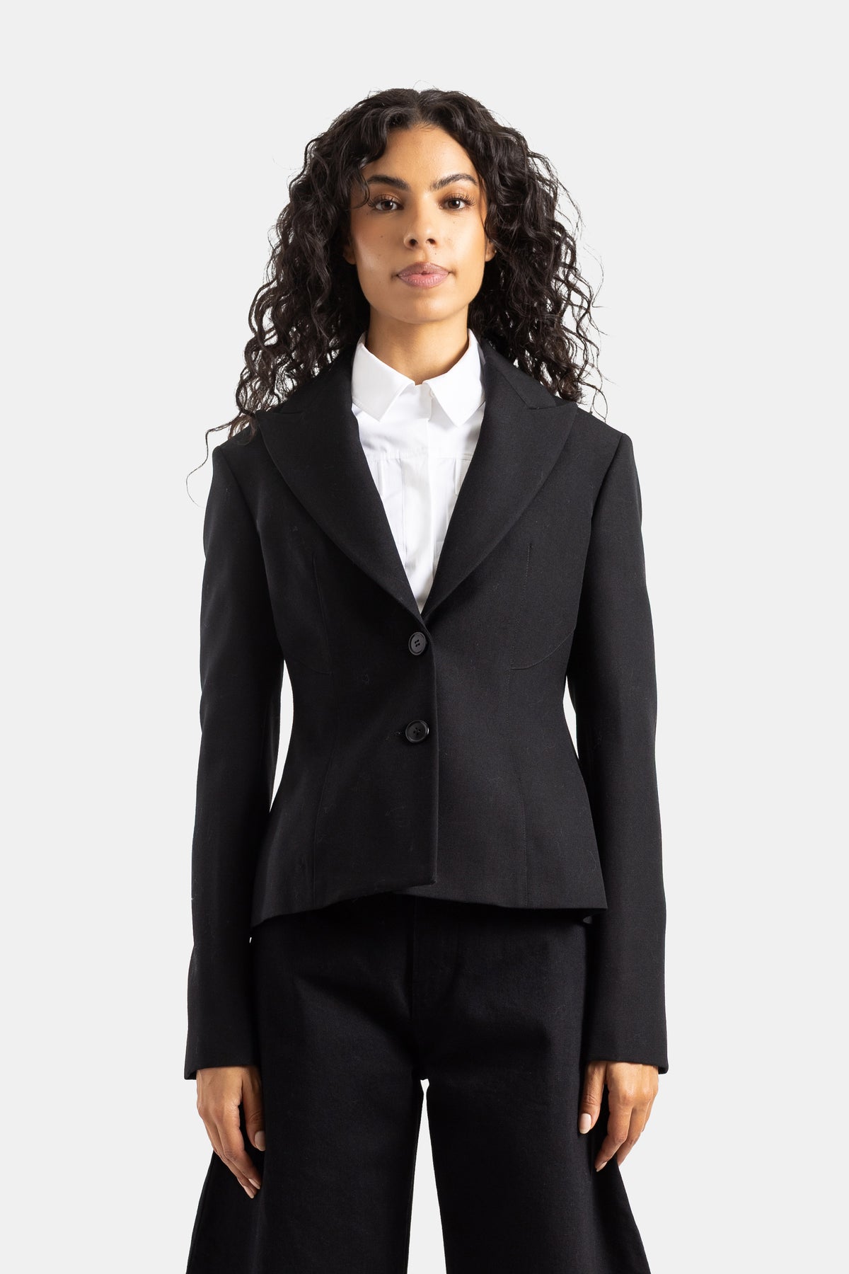 Giacca sartoriale sfiancata Maison Alaïa con baschina, revers a dente e maniche lunghe in pura lana nera