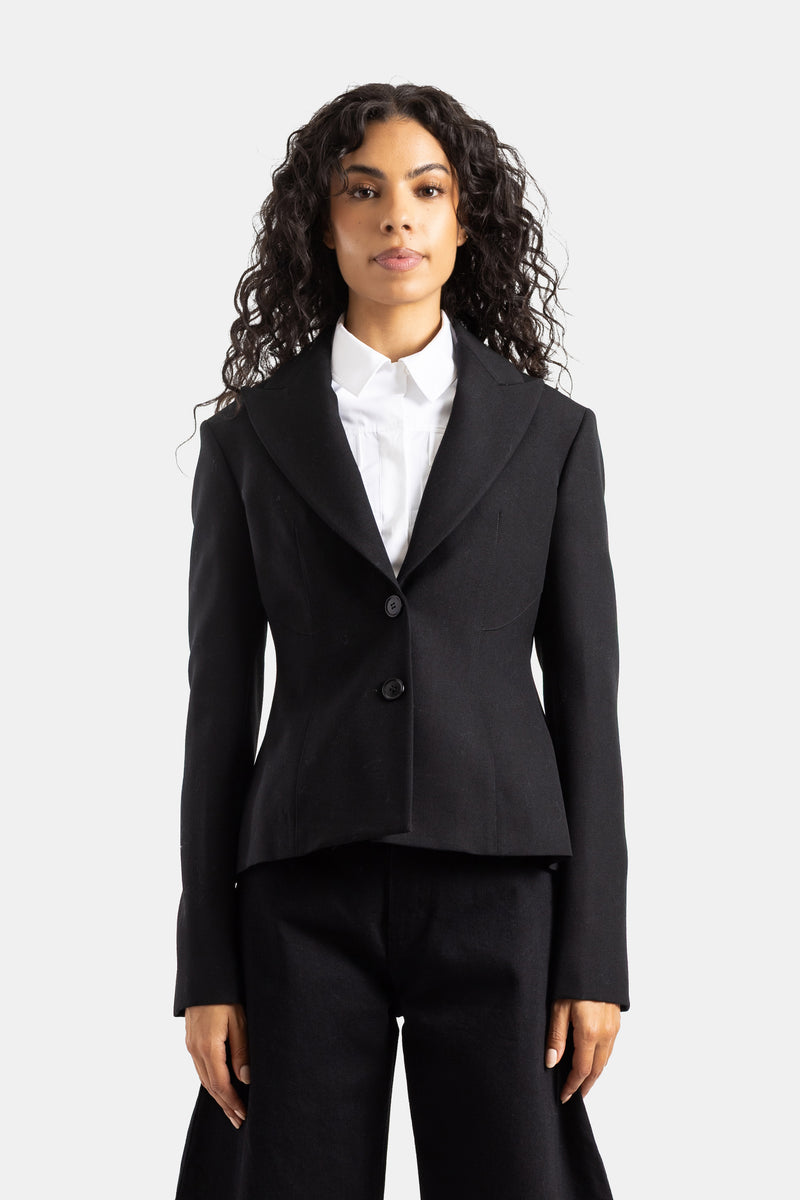 Maison Alaïa（メゾン アライア）による、ブラックのウール素材を使用した、ウエストを細く見せるフェミニンなペプラムデザインとクラシックなノッチドラペルが特徴的な長袖テーラードジャケットのハンガーカット。