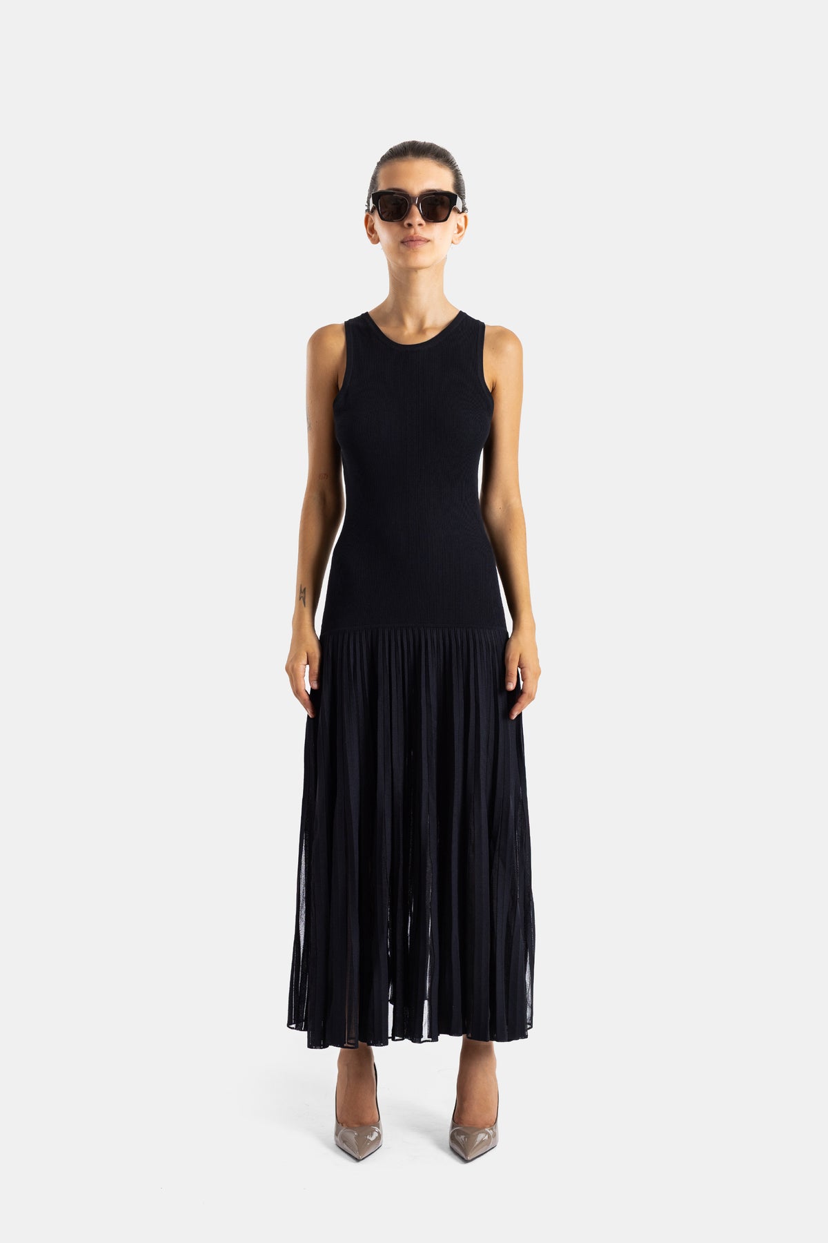 Maison Alaïa robe midi noire vue de face silhouette ajustée haut côtelé et jupe plissée transparente
