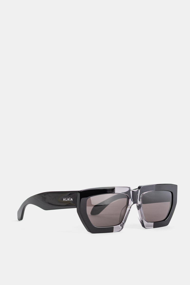 Maison Alaïa sunglasses vue trois quarts branches noires glossy contour inférieur cristal fumé collection FW26