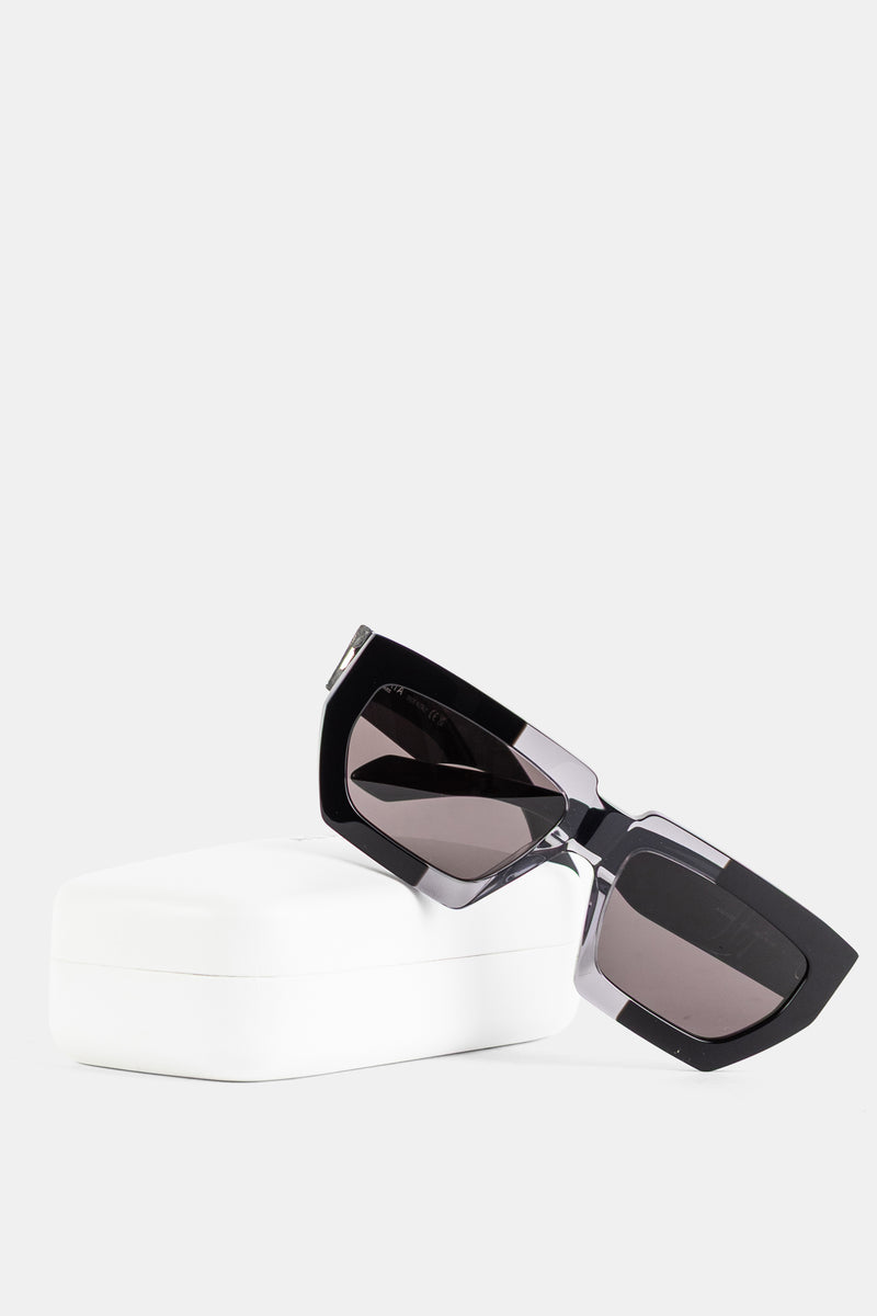 Maison Alaïa lunettes soleil posées sur étui blanc bicolore noir cristal fumé vue de profil FW26