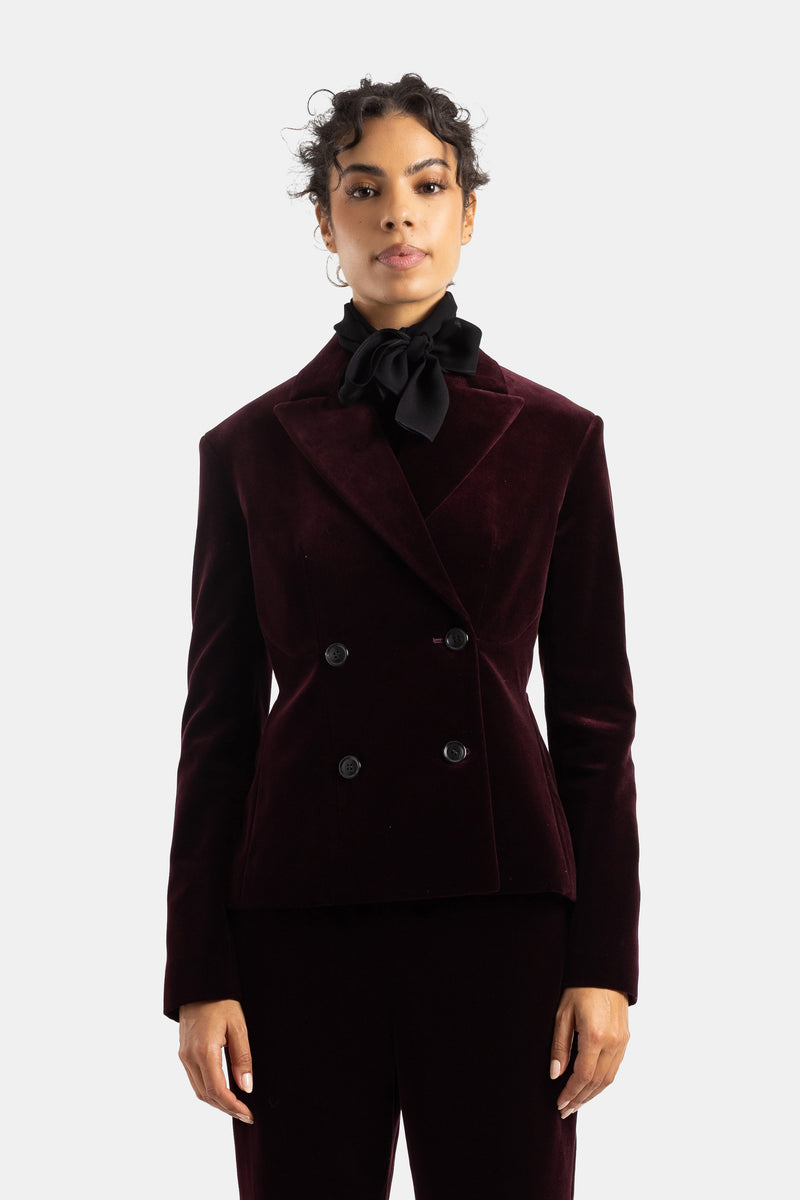 Maison Alaïaによるオーベルジーヌ（深みのあるナス紺色）の高級感漂うベルベット素材を使用した、レディース用の幅広ラペルが美しい仕立てのフィッテッドダブルジャケット。エレガントなシルエットを演出。