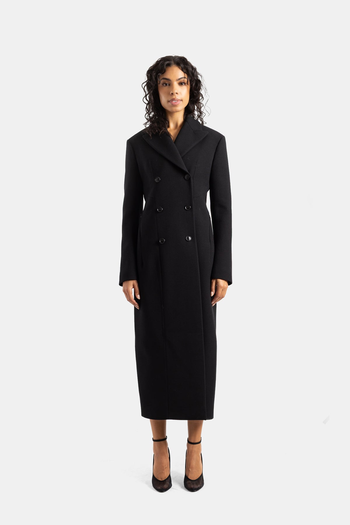 Maison Alaïa women's long double-breasted fitted coat in black wool with a notched collar and structured shoulders.