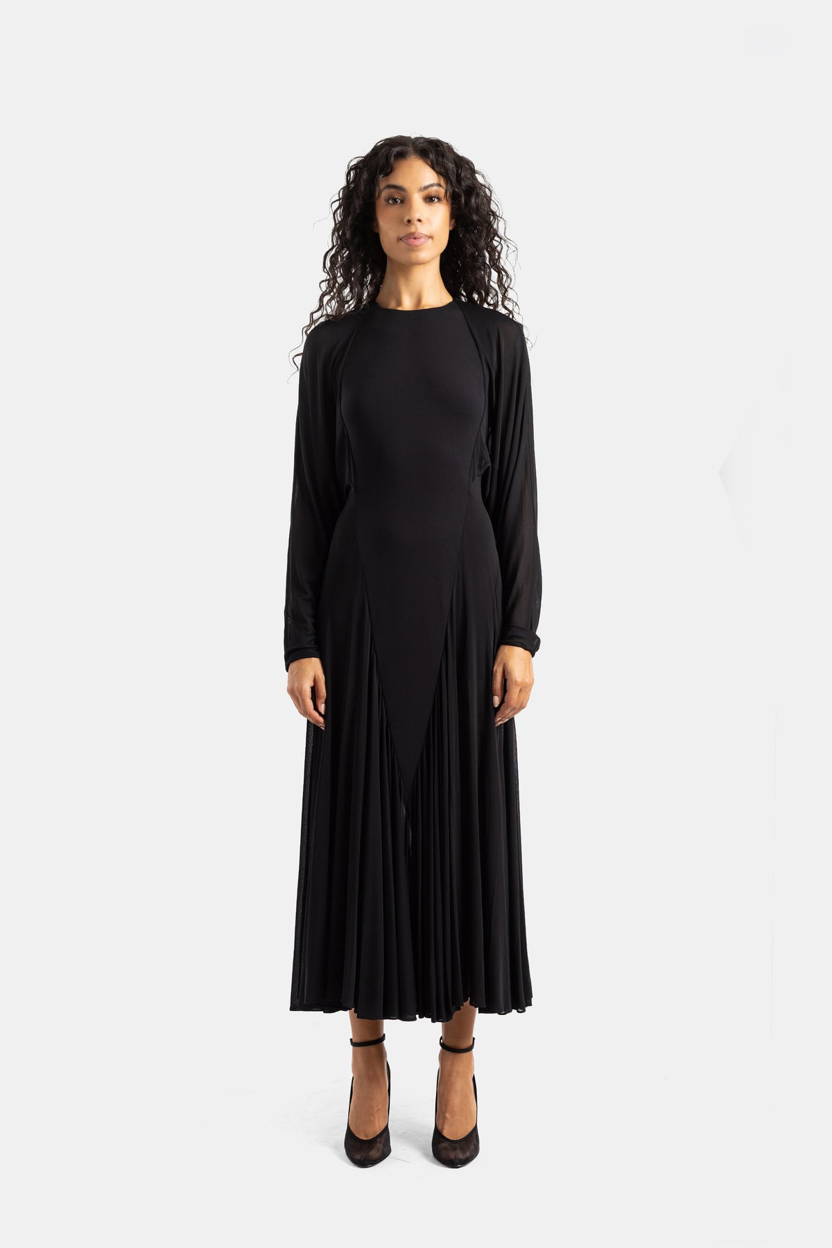 Abito lungo nero Maison Alaïa con maniche a pipistrello, girocollo e gonna a godet plissettata in jersey fluido.