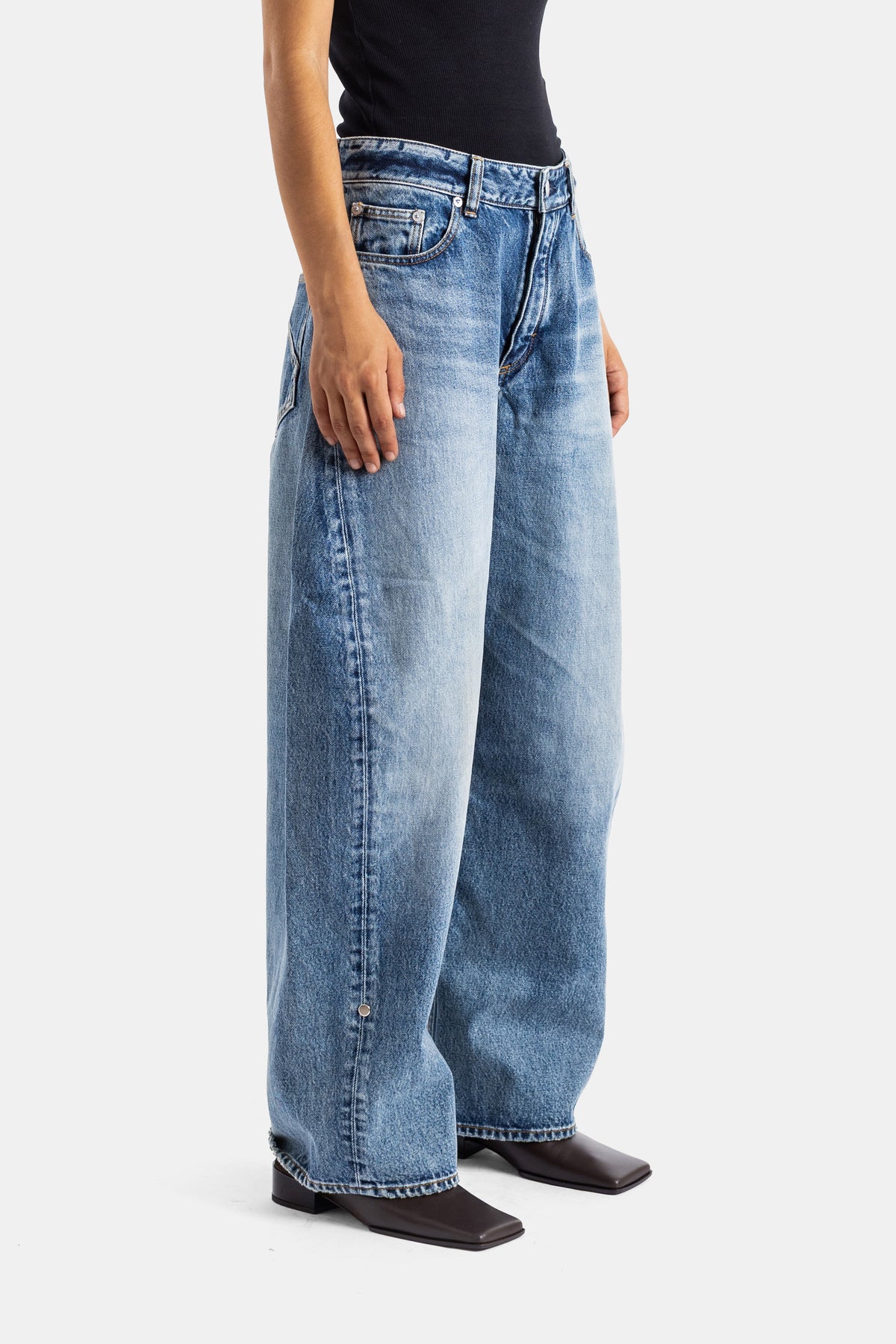 Maison Alaïa jean Rodeo large jambe évasée denim bleu usé vue de côté avec boots carrées