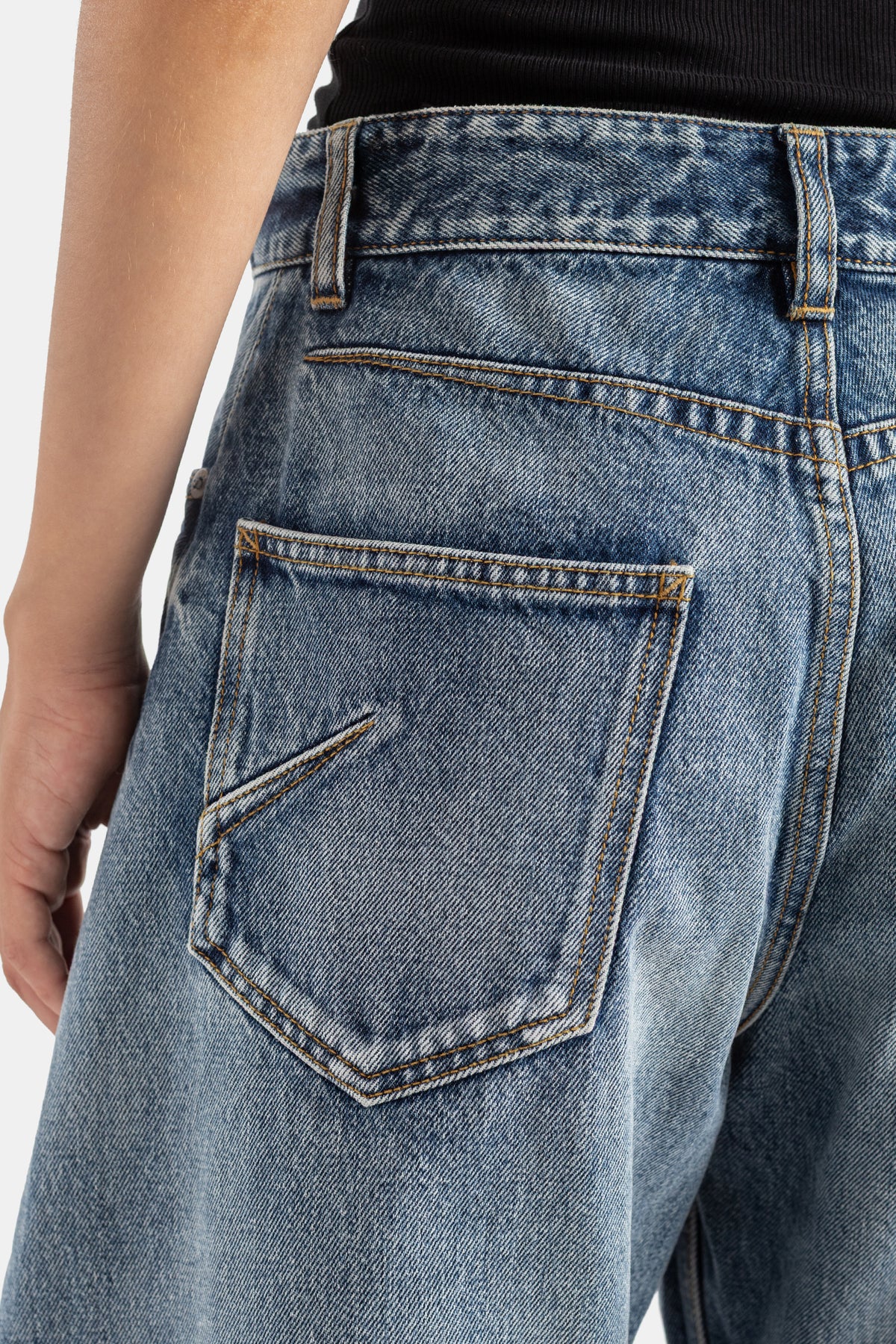Maison Alaïa jean Rodeo zoom poche arrière festonnée denim bleu acide surpiqûres dorées gros plan