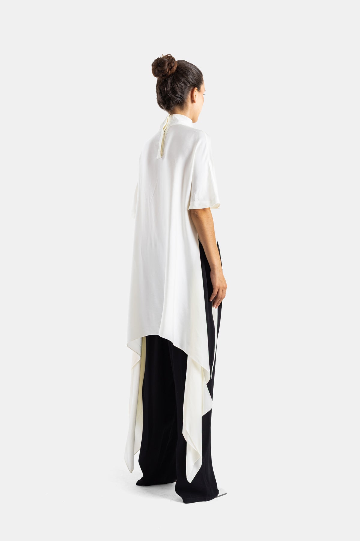 Maison Alaïa top asymétrique crème dos dévoilant traîne drapée fluide, porté avec pantalon large bicolore noir et blanc