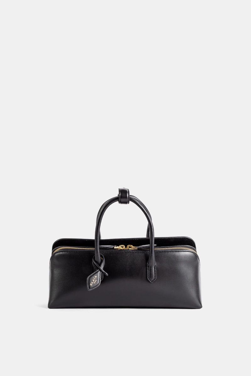 Vorderseite der Maison Alaïa Delta Small aus glänzendem schwarzem Leder mit goldenem Reißverschluss und Signatur-Charm