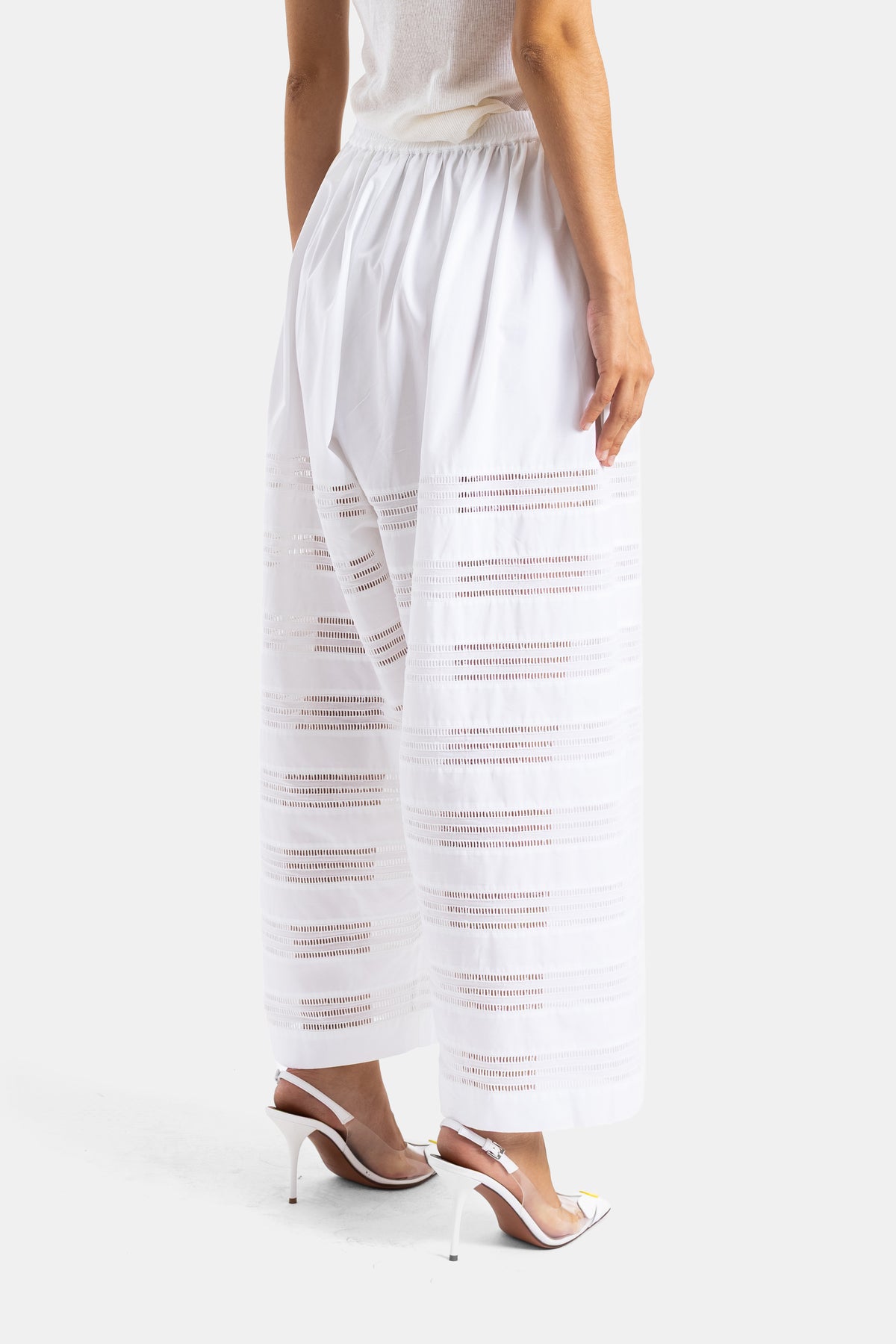 Maison Alaïa pantalon blanc vue dos ceinture élastique ajourée bandes transparentes escarpins slingback blancs