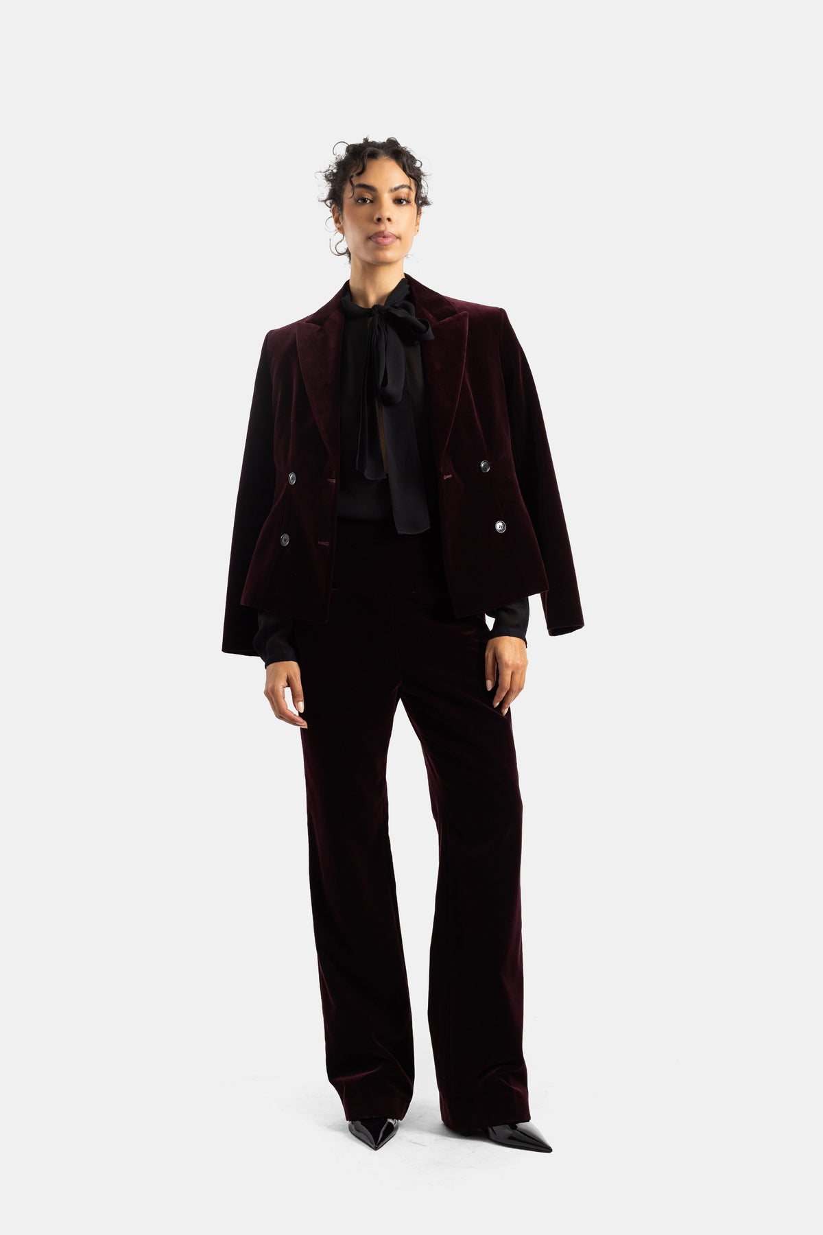 Completo in velluto melanzana Maison Alaïa indossato, blazer doppiopetto corto e pantaloni a vita alta