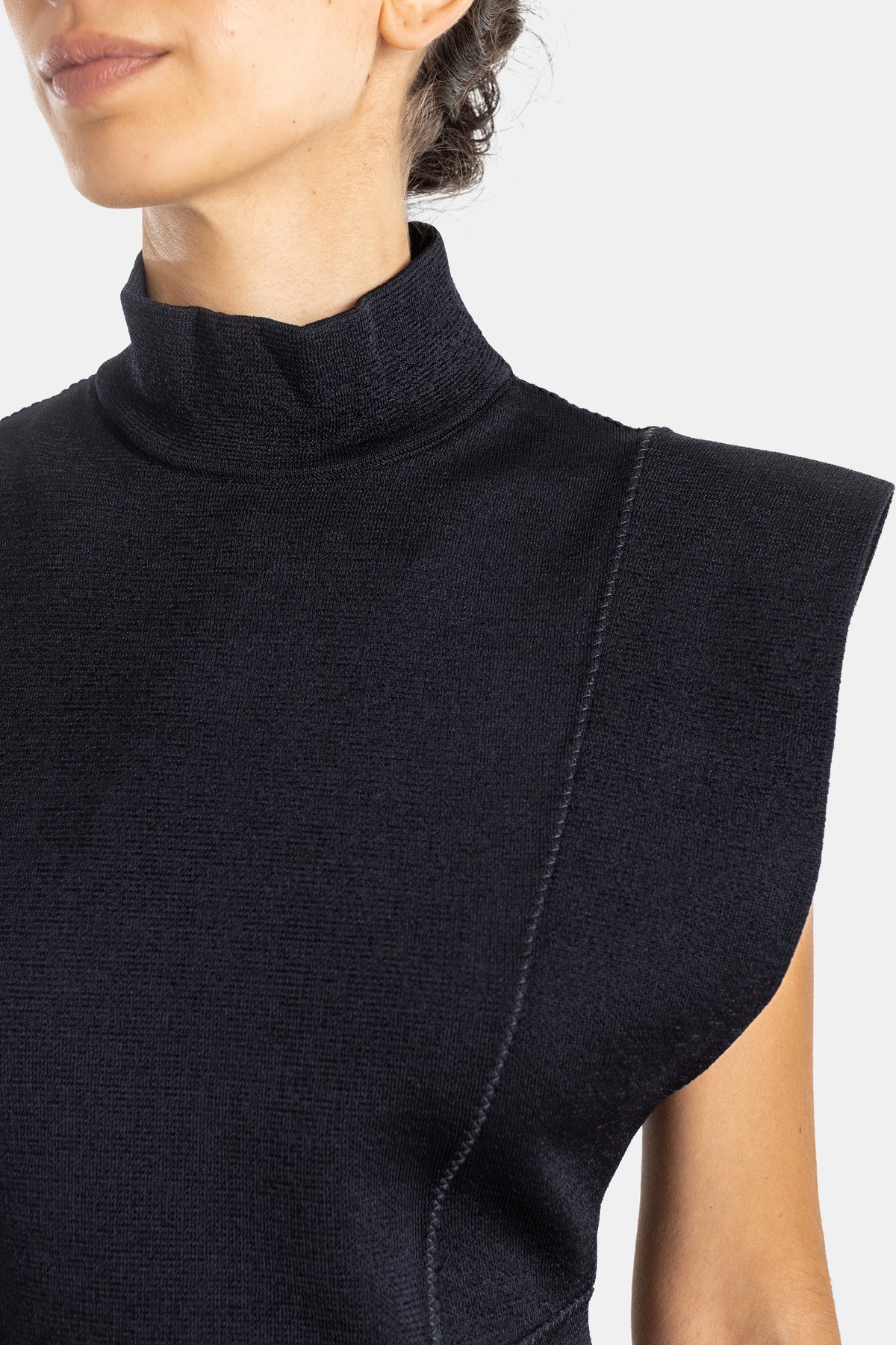 Maison Alaïa robe maille compacte noire col roulé gros plan encolure couture zénithale épaule carrée