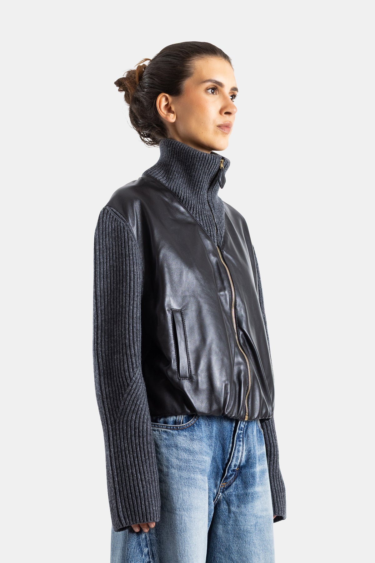 Maison Alaïa veste femme profil latéral, corps cuir souple noir, manches tricot côtelé gris, fermeture dorée