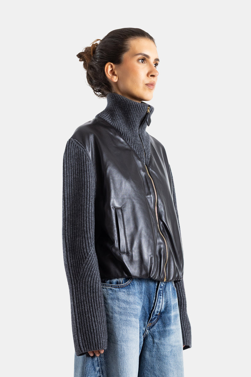 Maison Alaïa veste femme profil latéral, corps cuir souple noir, manches tricot côtelé gris, fermeture dorée