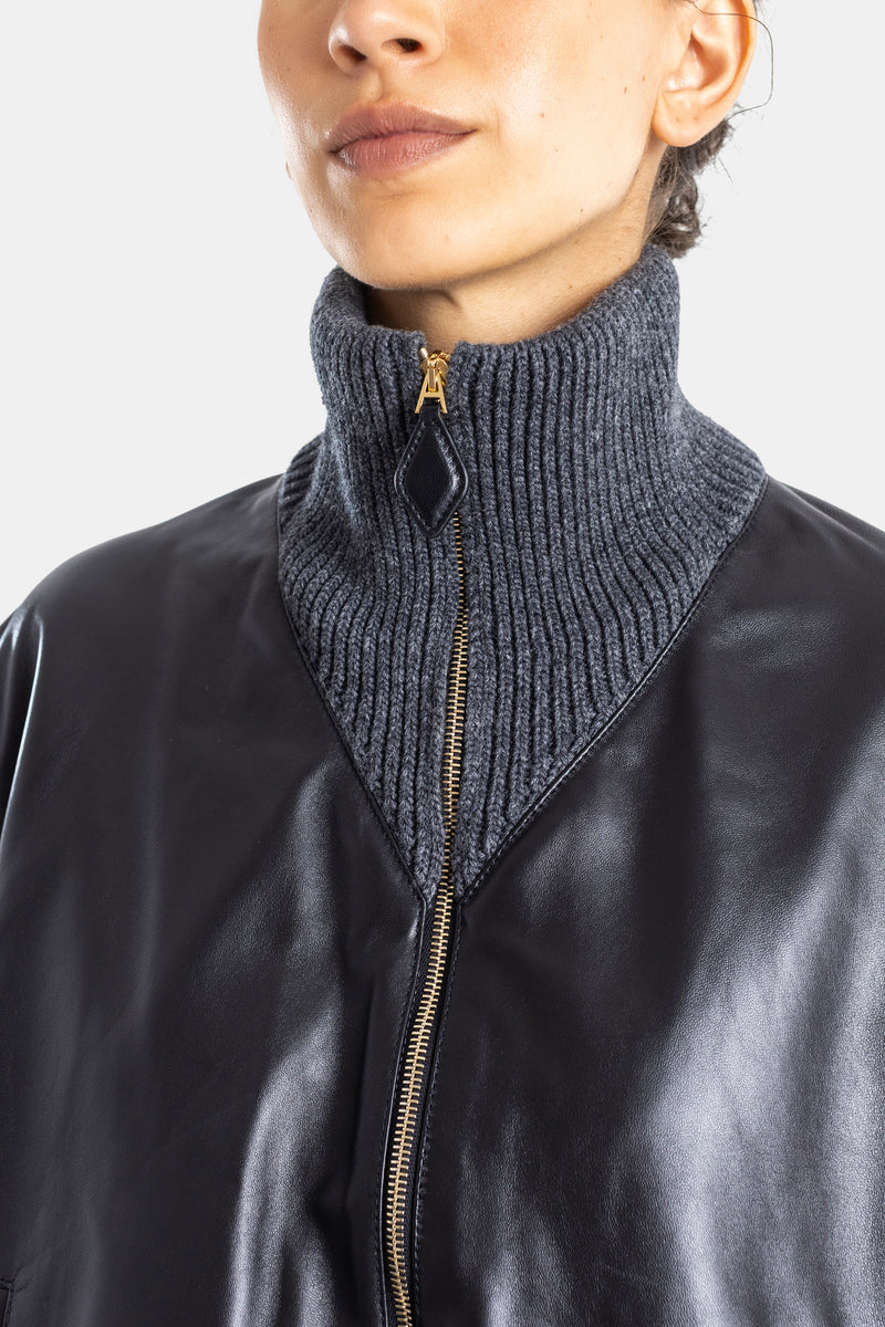 Maison Alaïa zoom col zippé doré, intérieur tricot côtelé gris anthracite, détail tirette losange cuir noir