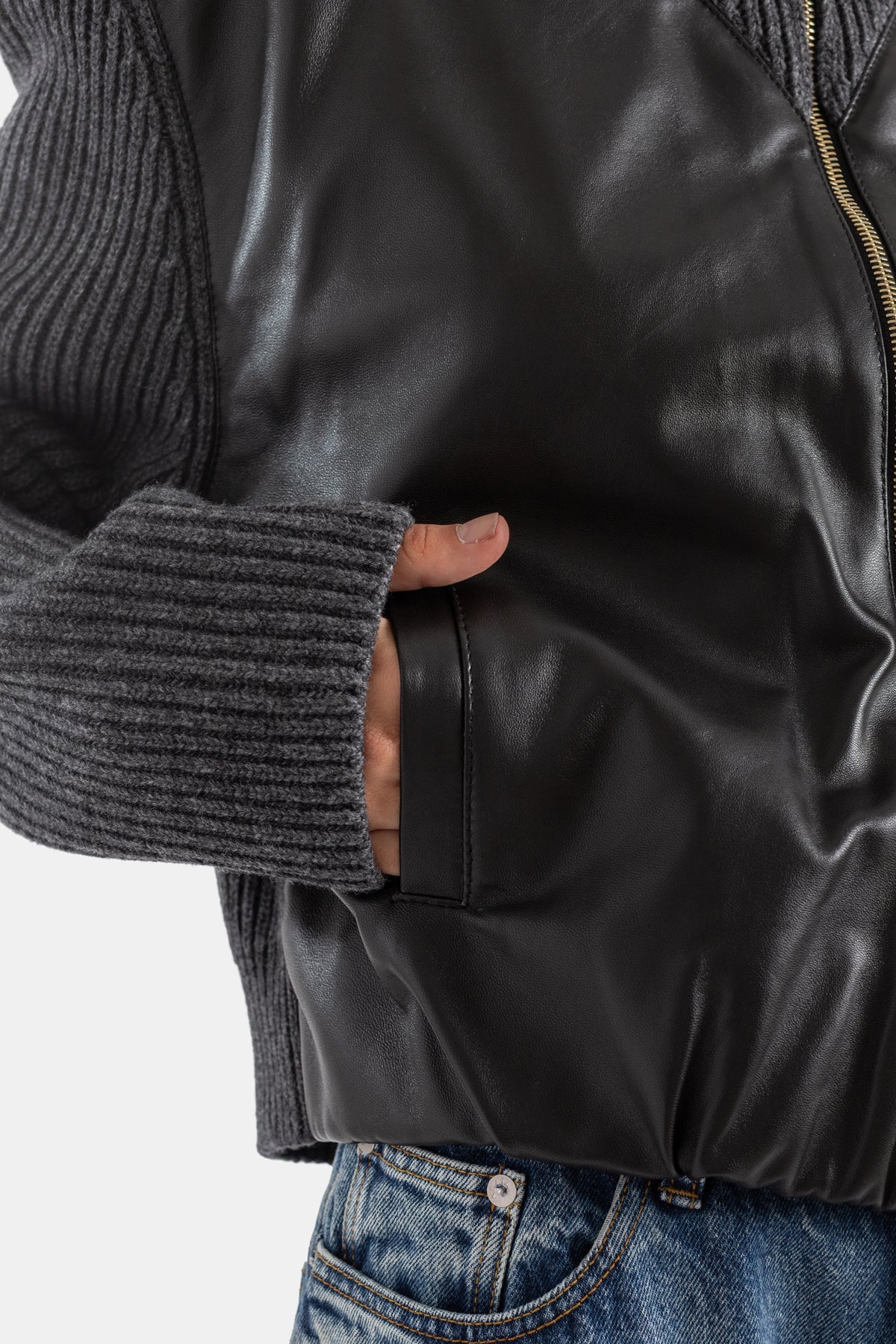 Maison Alaïa poche latérale cuir noir, poignet tricot côtelé gris, main glissée, détail construction hybride