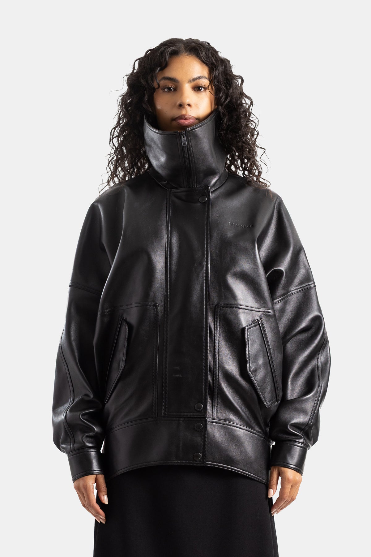 Giubbotto bomber oversize Balenciaga in pelle nera, con collo alto con cerniera e maniche ampie da donna.