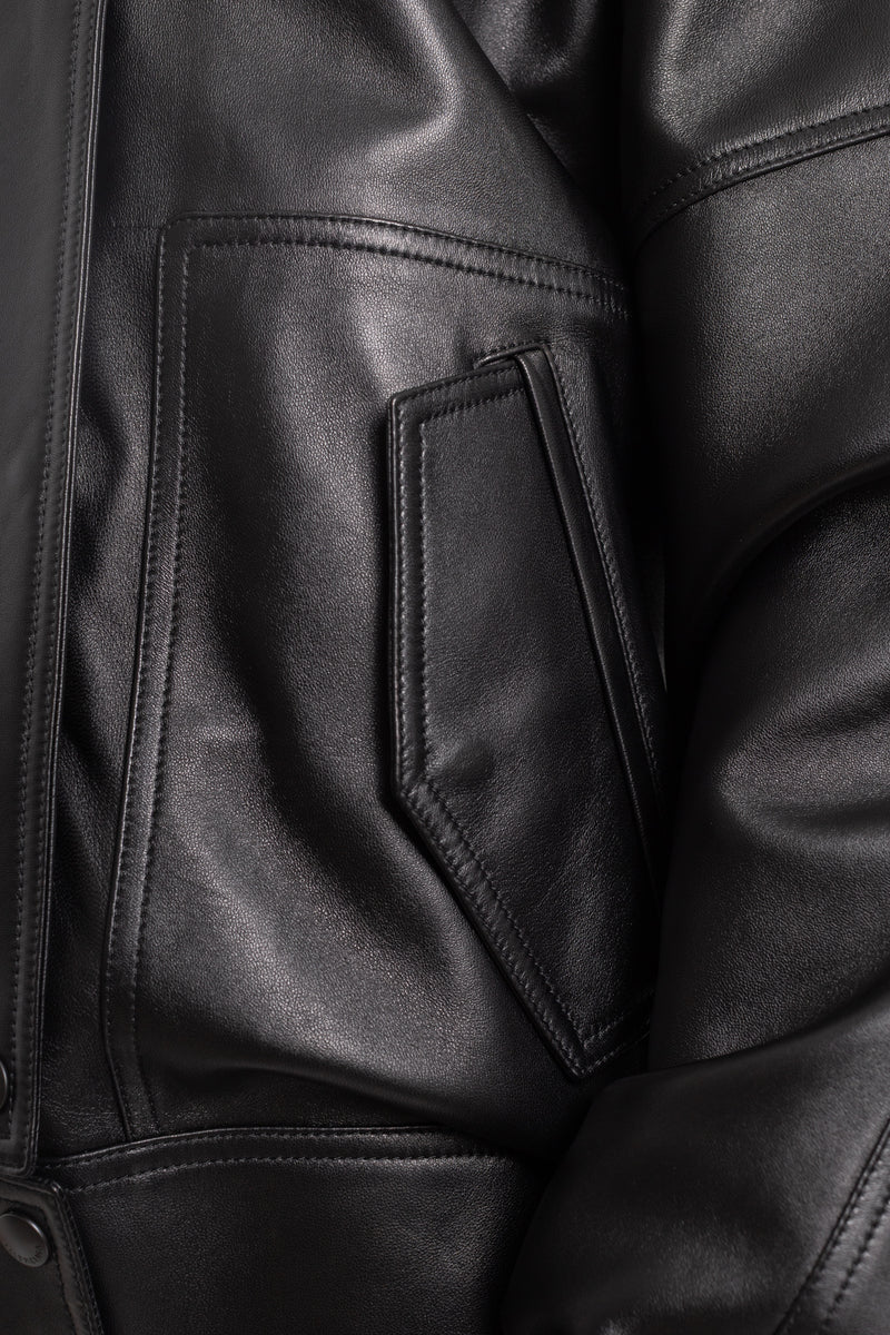 Dettaglio del giubbotto in pelle nera Balenciaga con tasca applicata asimmetrica, cuciture a vista e finitura liscia.