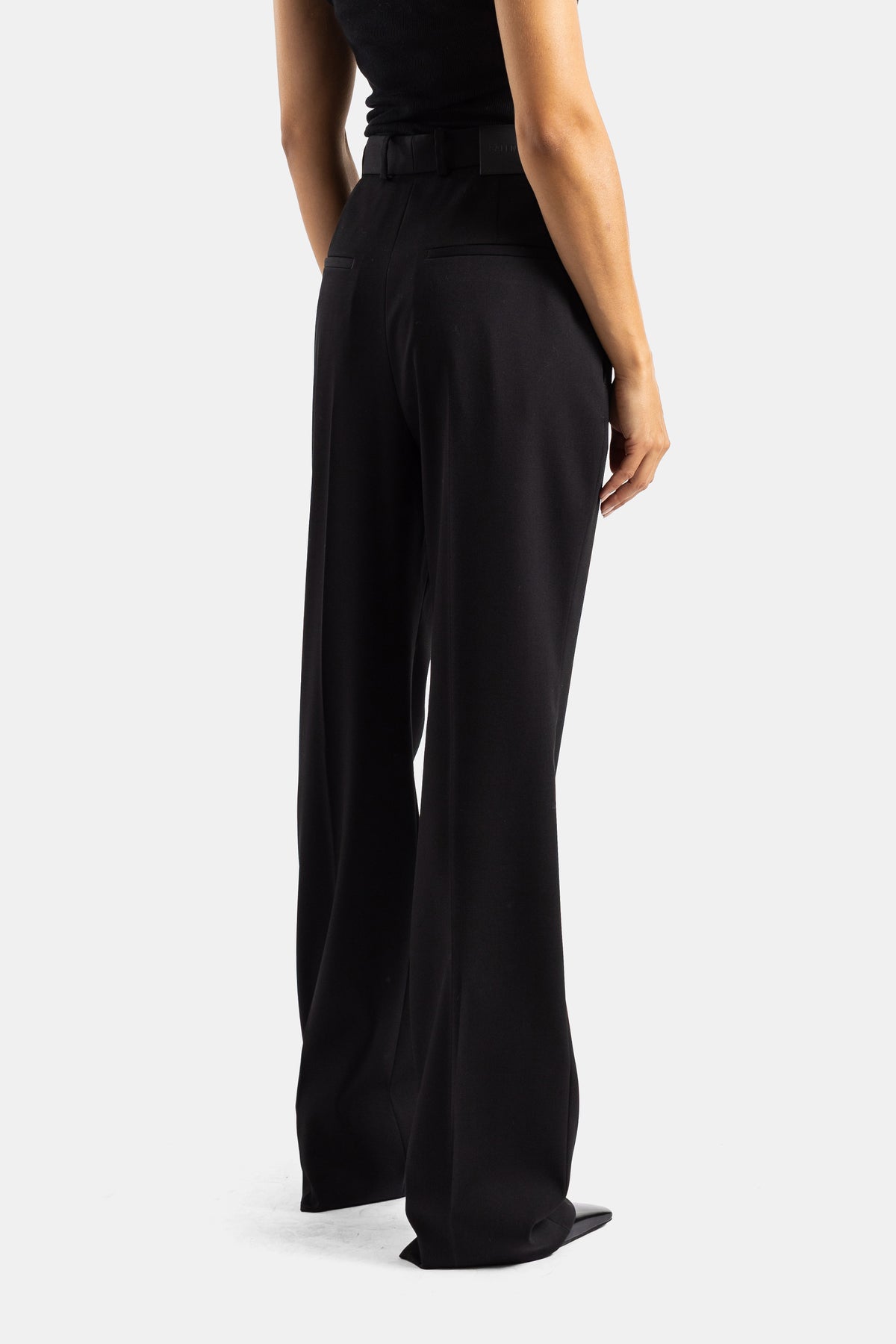 Balenciaga zwarte stretchwollen broek met grijs geribd vest en taupe suède tas, luxe totale look voor dames.