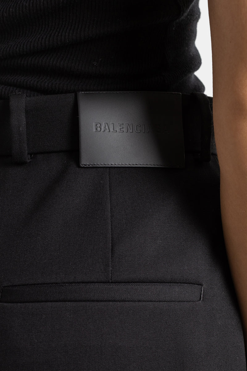 Balenciaga high-waist pantalon achterkant, zwarte stretchwol met gespriem en soepele val op zwarte laarsjes.