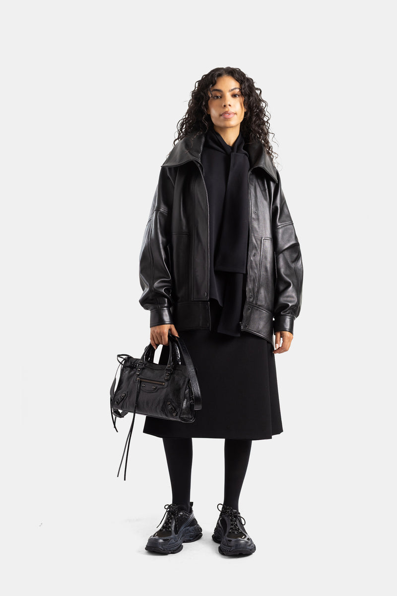 Gonna-pantalone Folded Balenciaga in lana nera indossata con giacca oversize in pelle e borsa da città.