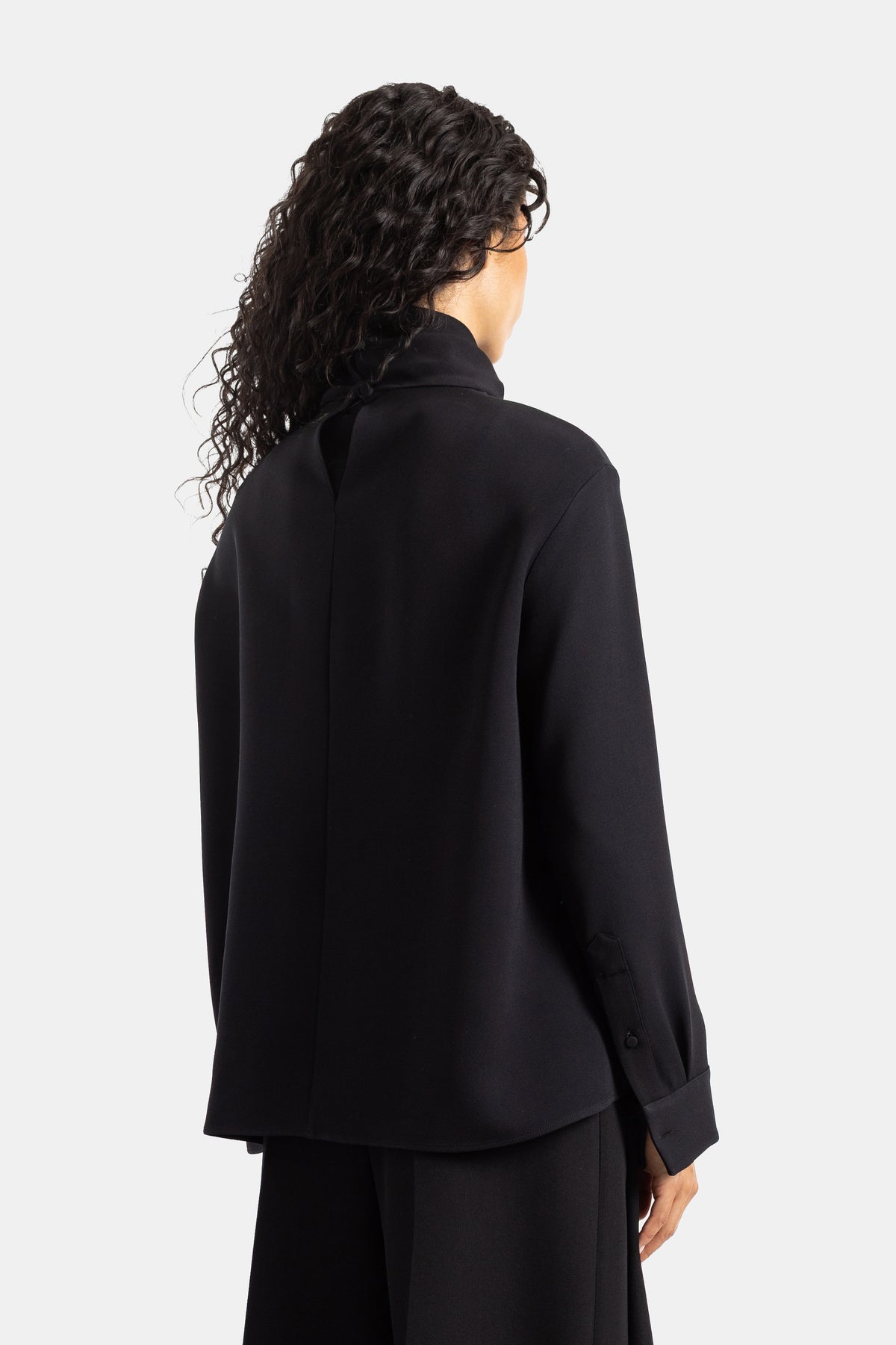 Retro della blusa nera Balenciaga con cucitura centrale, in crêpe fluido, maniche lunghe e polsini con bottoni.