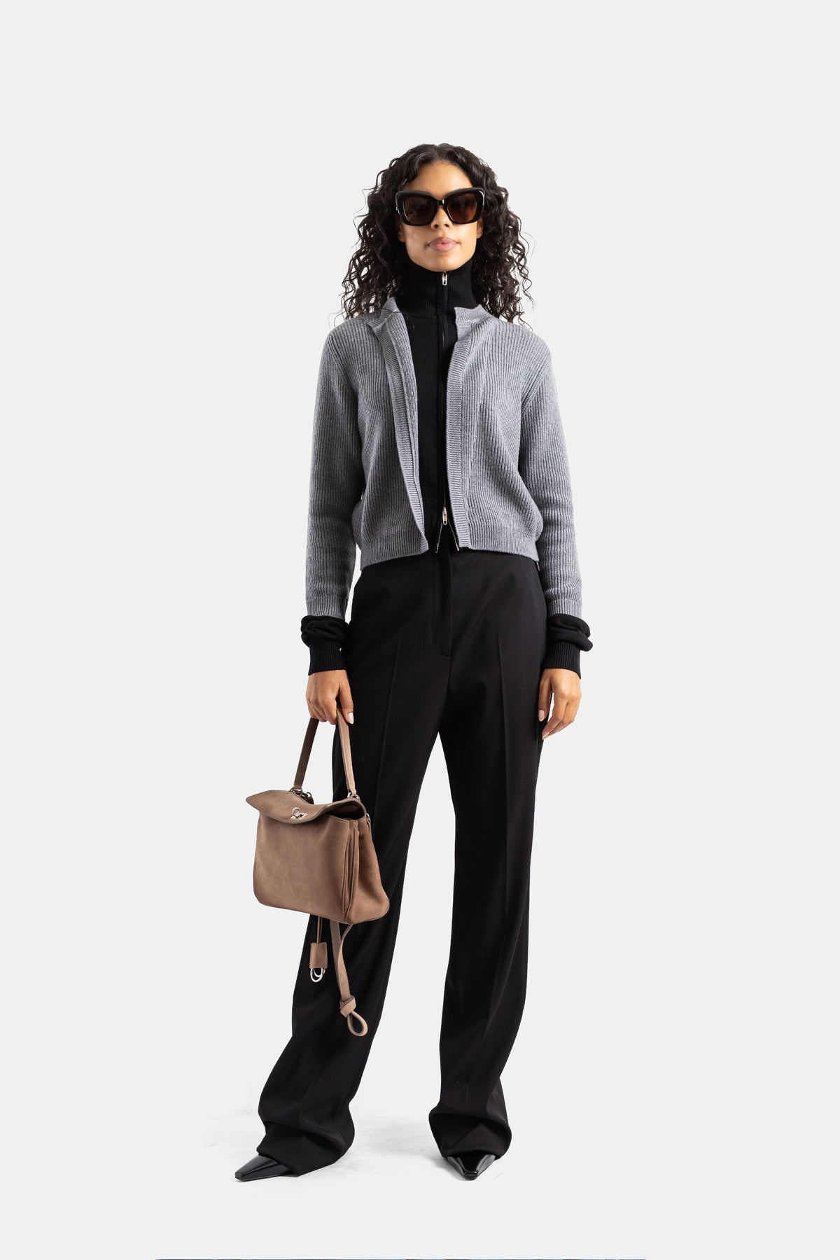 Cardigan grigio zippato Balenciaga indossato con pantaloni neri larghi e borsa taupe per un look donna di lusso.