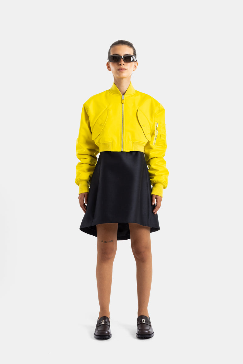 Balenciaga bomber jaune crop femme porté avec jupe noire, loafers et lunettes tendance, look avant-garde