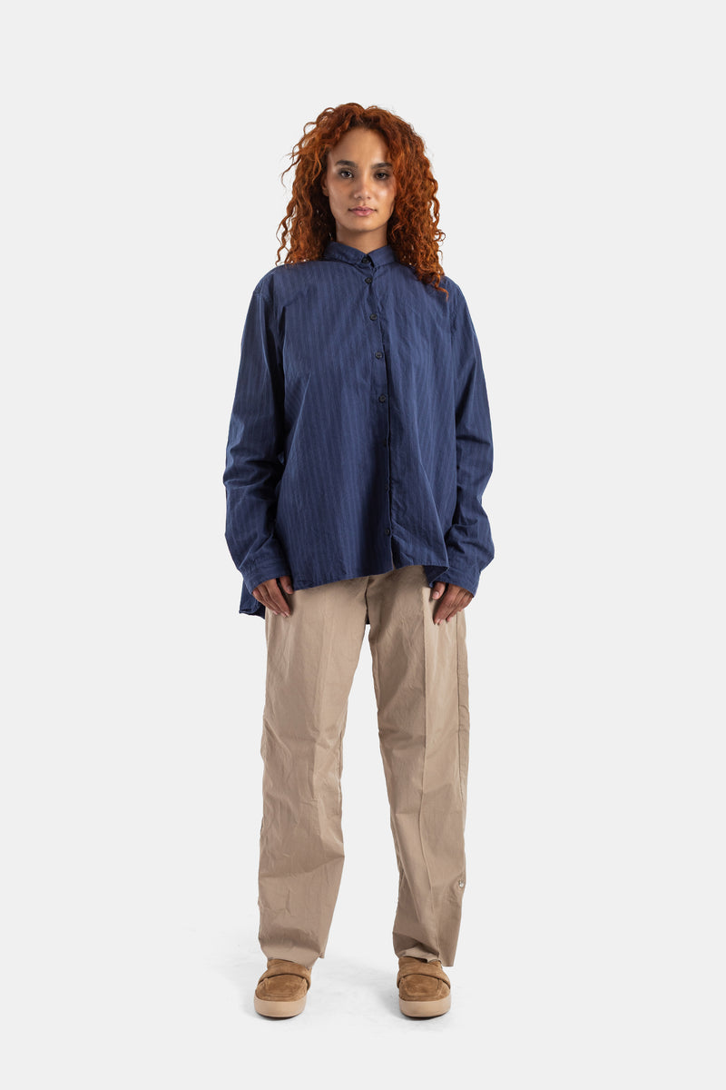 Pantalón Bergfabel Silvy de algodón arrugado beige con camisa azul oversize y zapatillas de ante camel