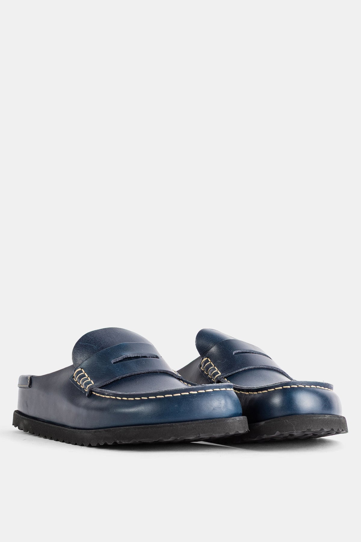 斜め後ろから捉えたBirkenstock 1774のNaplesミュール。パティナ仕上げのネイビーブルーレザーの美しい質感と、耐久性に優れたブラックのラバーソールのコントラストが際立つ一足。