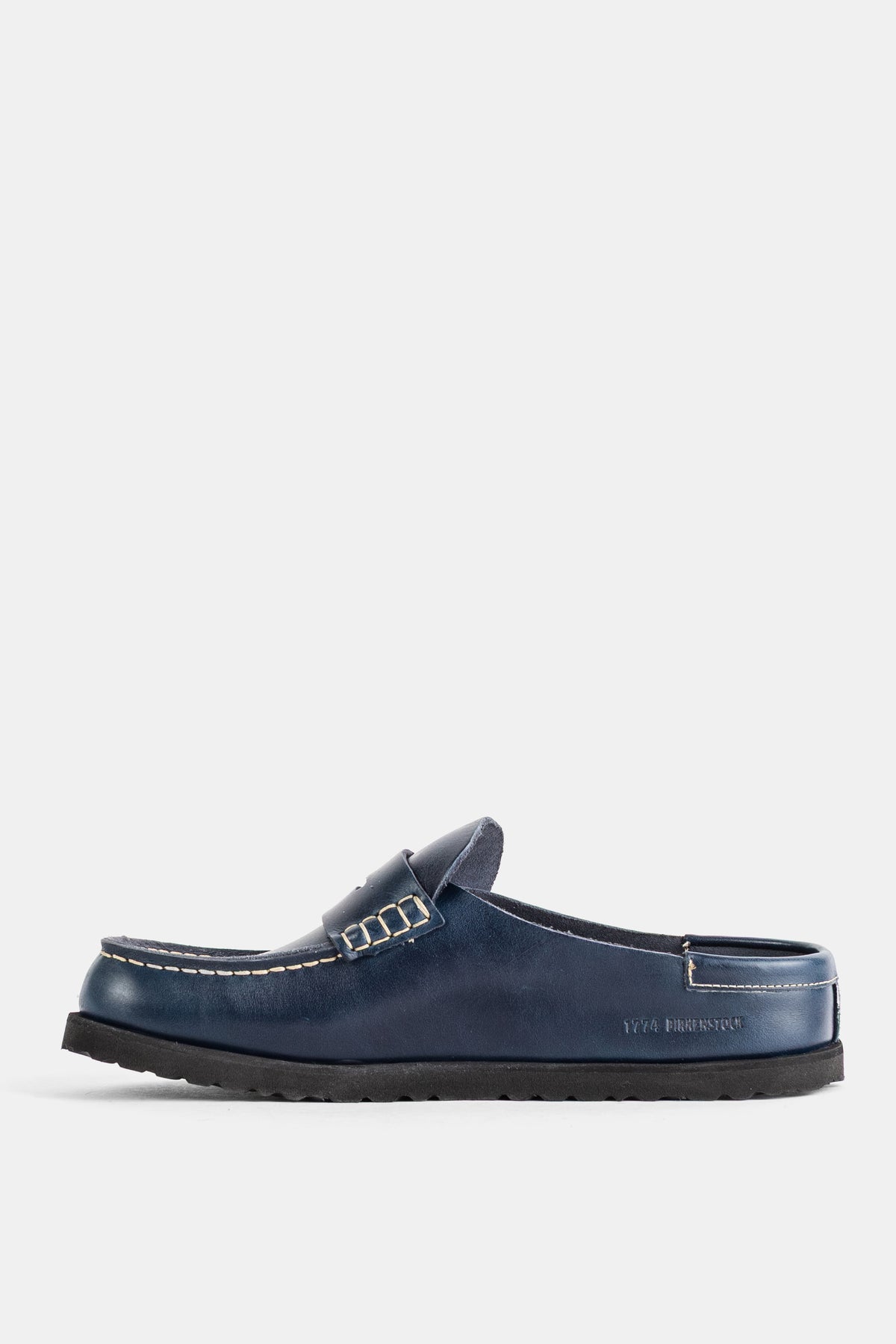 サイドプロファイルで見るBirkenstock 1774のNaplesネイビーミュール。ペニーサドルのディテールと、アッパーに映える繊細なホワイトステッチの職人技が光る贅沢なディテール。