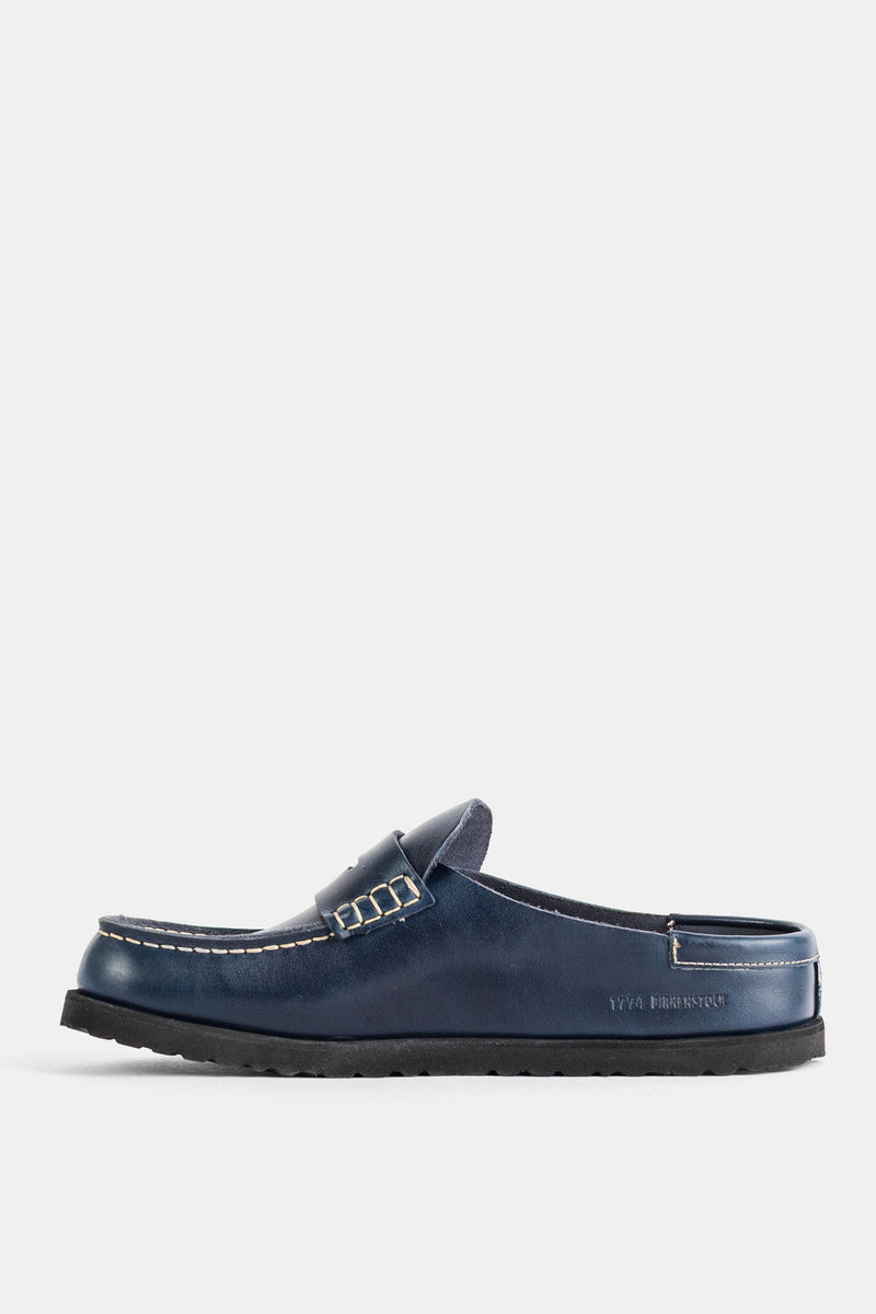 サイドプロファイルで見るBirkenstock 1774のNaplesネイビーミュール。ペニーサドルのディテールと、アッパーに映える繊細なホワイトステッチの職人技が光る贅沢なディテール。
