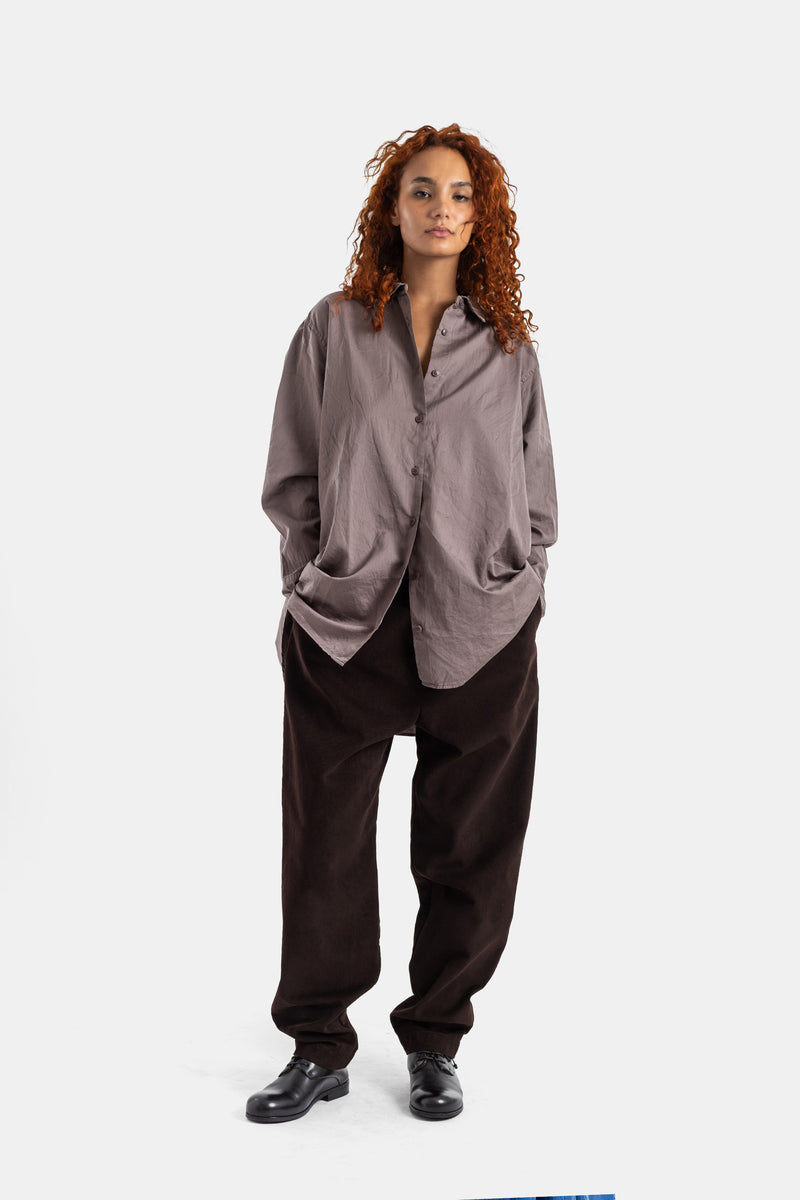 Casey Casey oversize Pi shirt worn open over brown trousers, soft taupe cotton, casual look with loose volume.