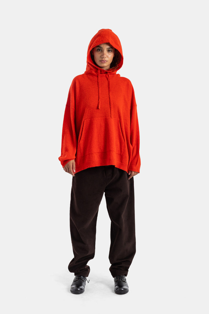 Casey Casey women's bright red bouclé knit hoodie, oversized silhouette worn with chocolate wide-leg trousers.