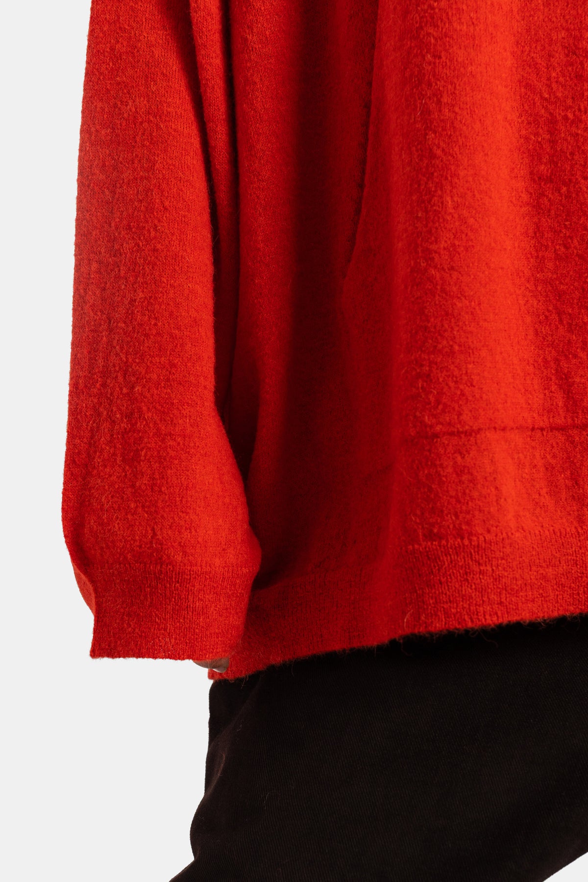 Casey Casey pull maille femme orange, focus bas de manche côtelé et ourlet asymétrique sur fond noir