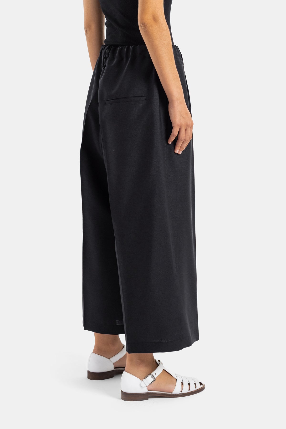 Sofie d'Hoore pantalon Pegged noir vue dos trois quarts poche passepoilée et jambe ample fluide
