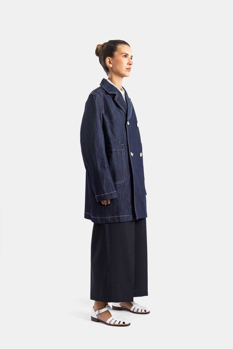 Sofie d'Hoore veste denim marine vue profil silhouette longue avec sandales blanches et jupe large noire