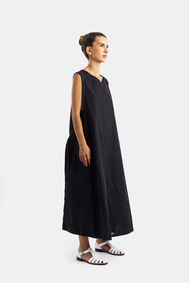 Casey Casey robe longue noire en coton froissé vue de profil avec poches latérales et sandales blanches
