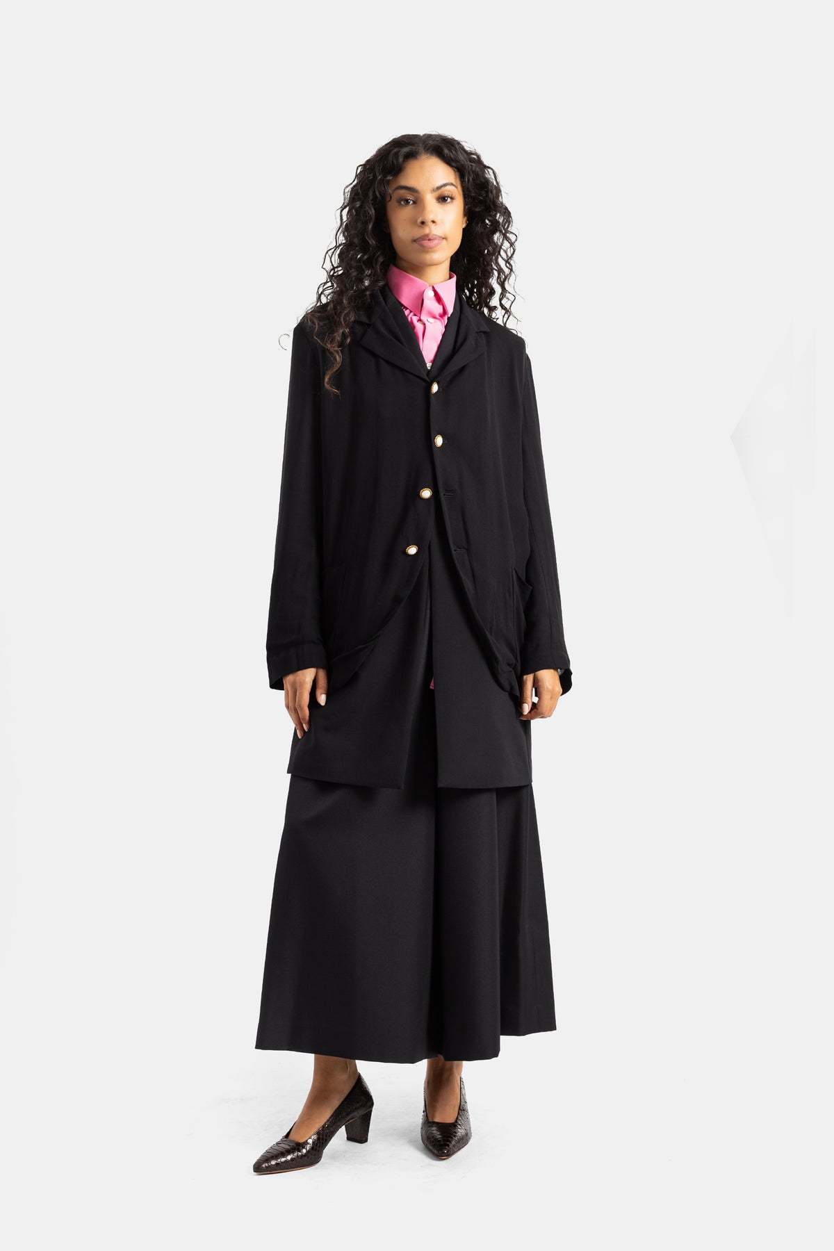 Casaco fluido Comme des Garçons preto silhueta vanguardista com camisa fúcsia gola franzida e saia palazzo